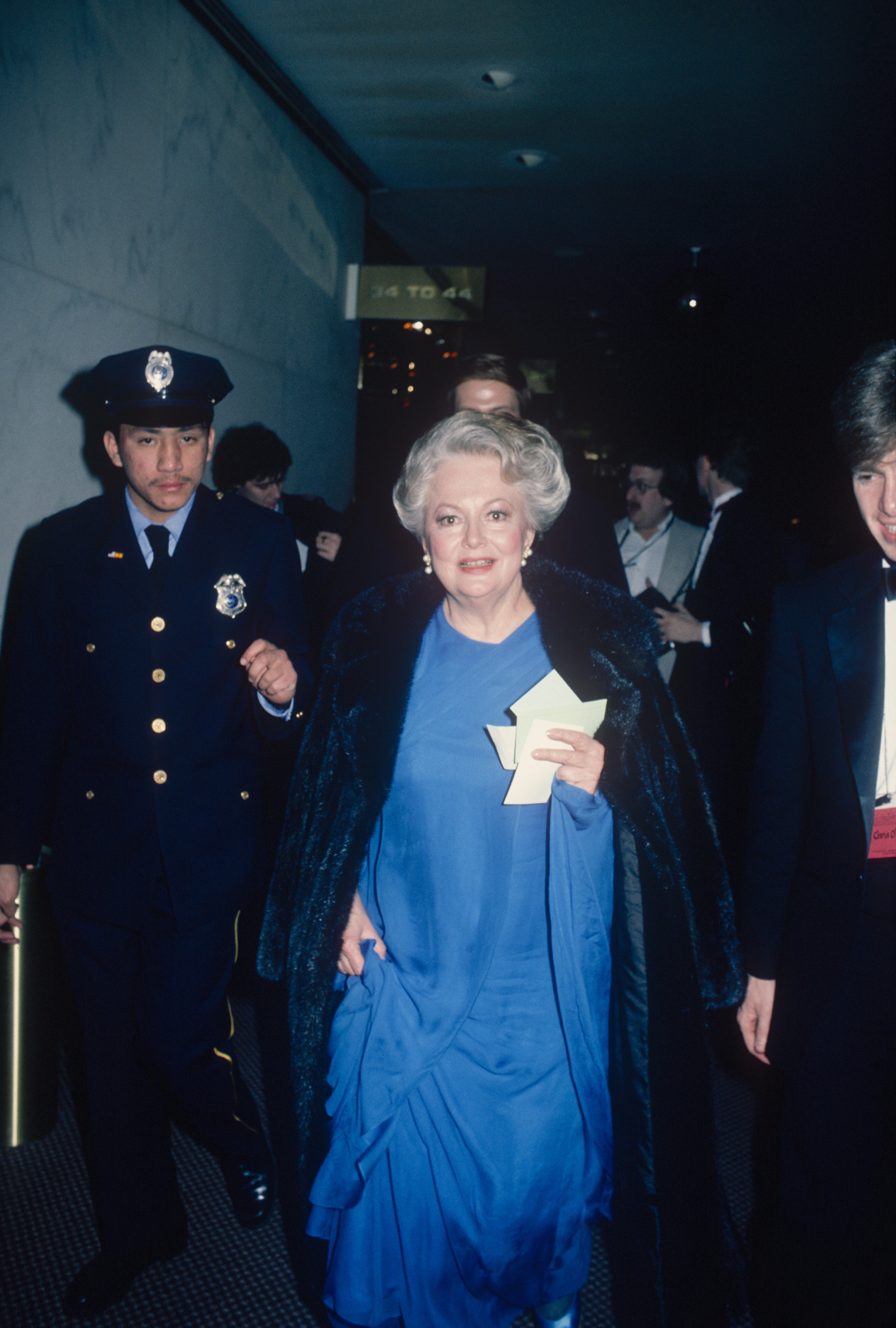 Olivia De Havilland escorted by a policeman, circa 1990. | Source: Art Zelin/Getty Images