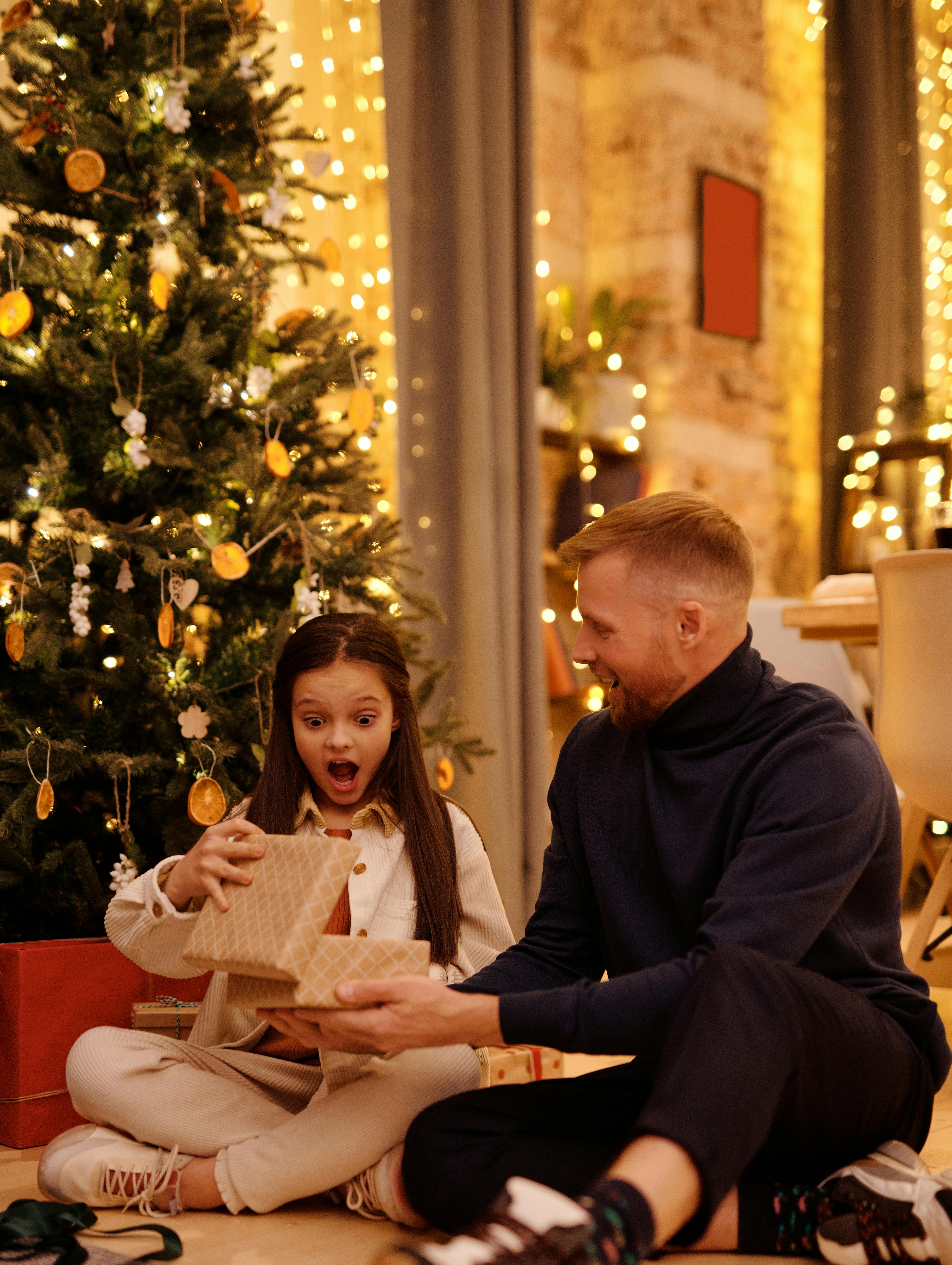 Excited girl looking at her gift with her dad | Source: Pexels