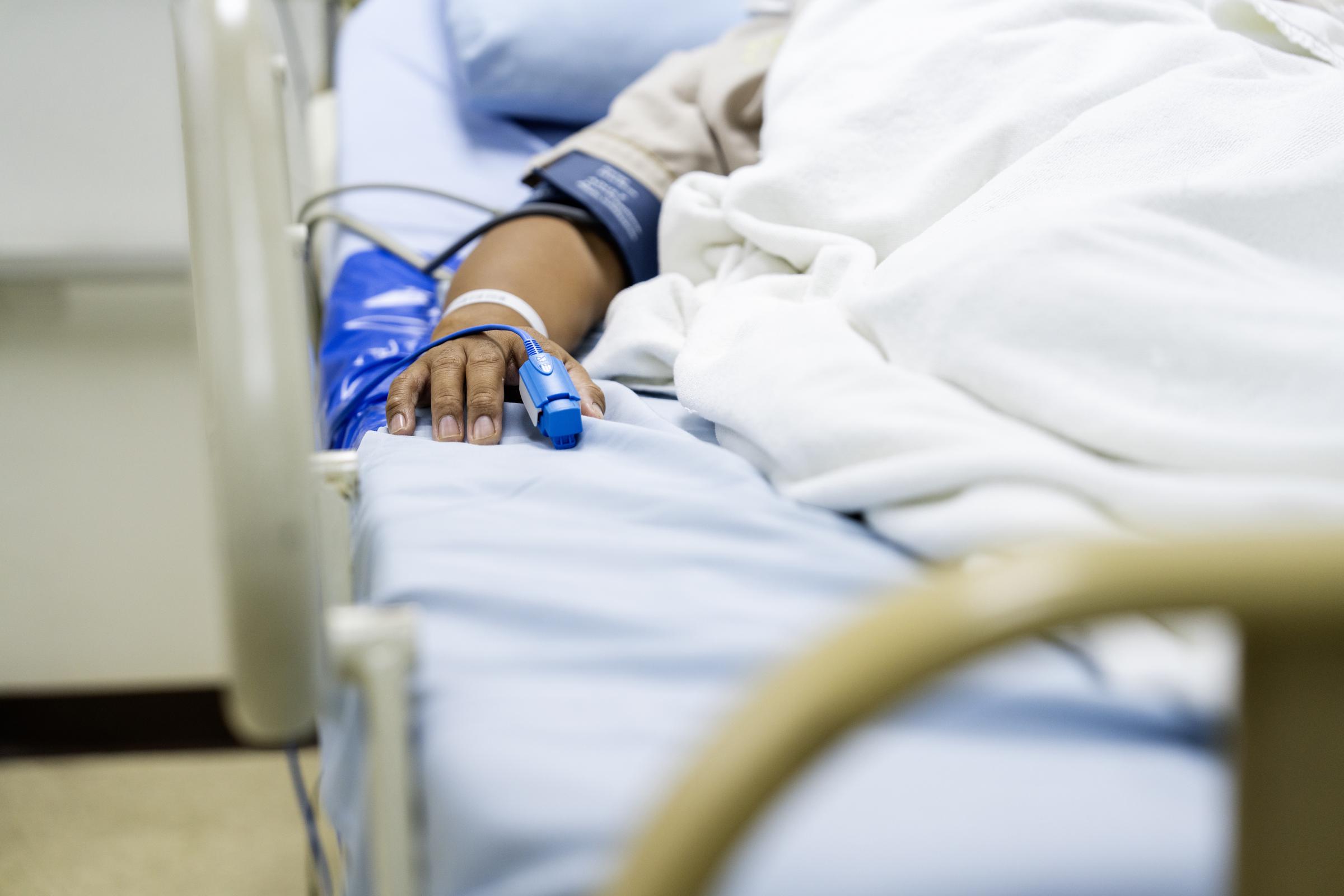 A patient lying in the hospital with a heart rate monitor on their finger | Source: Getty Images