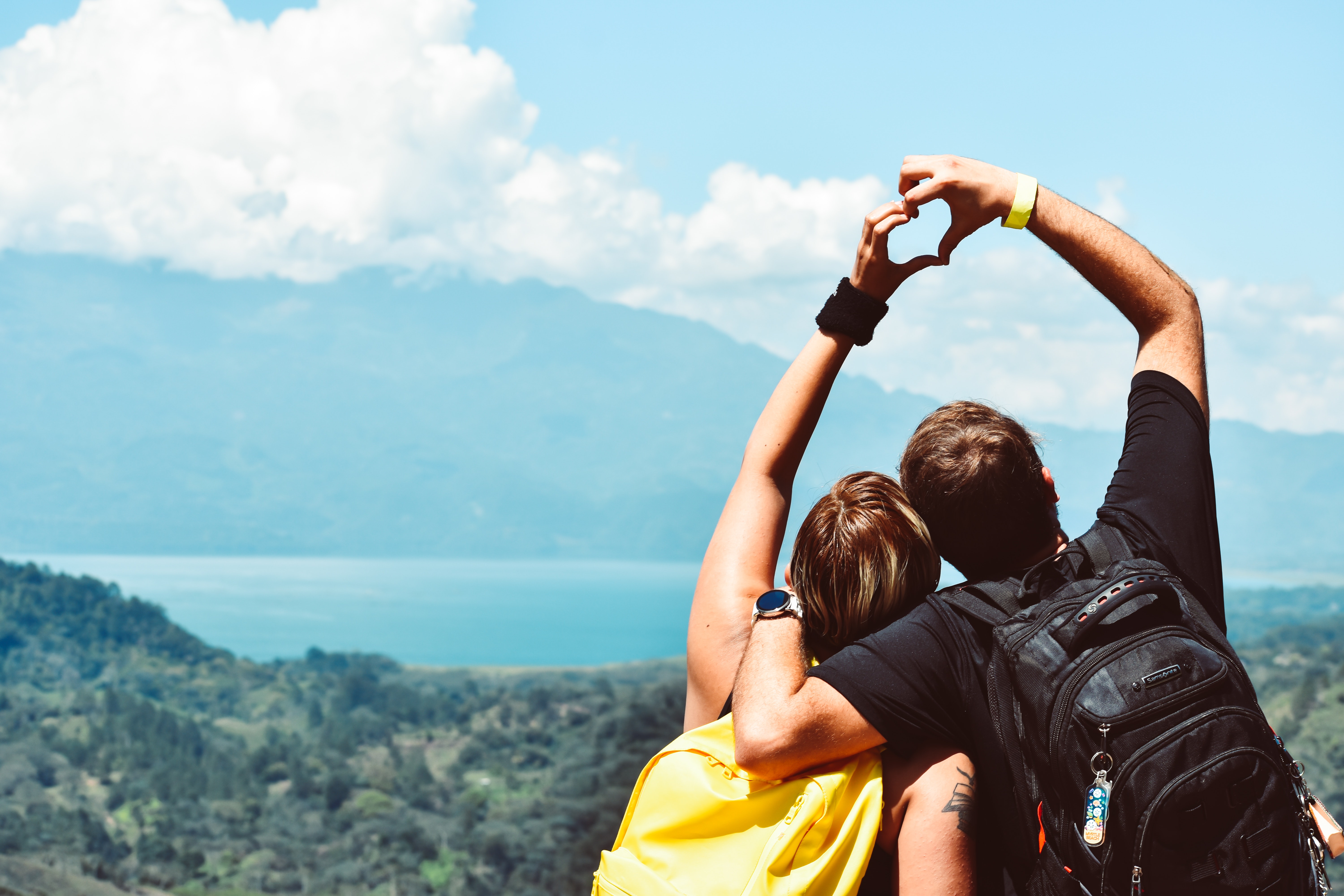 A couple hiking and creating a heart shape with their hands. | Source: Pexels
