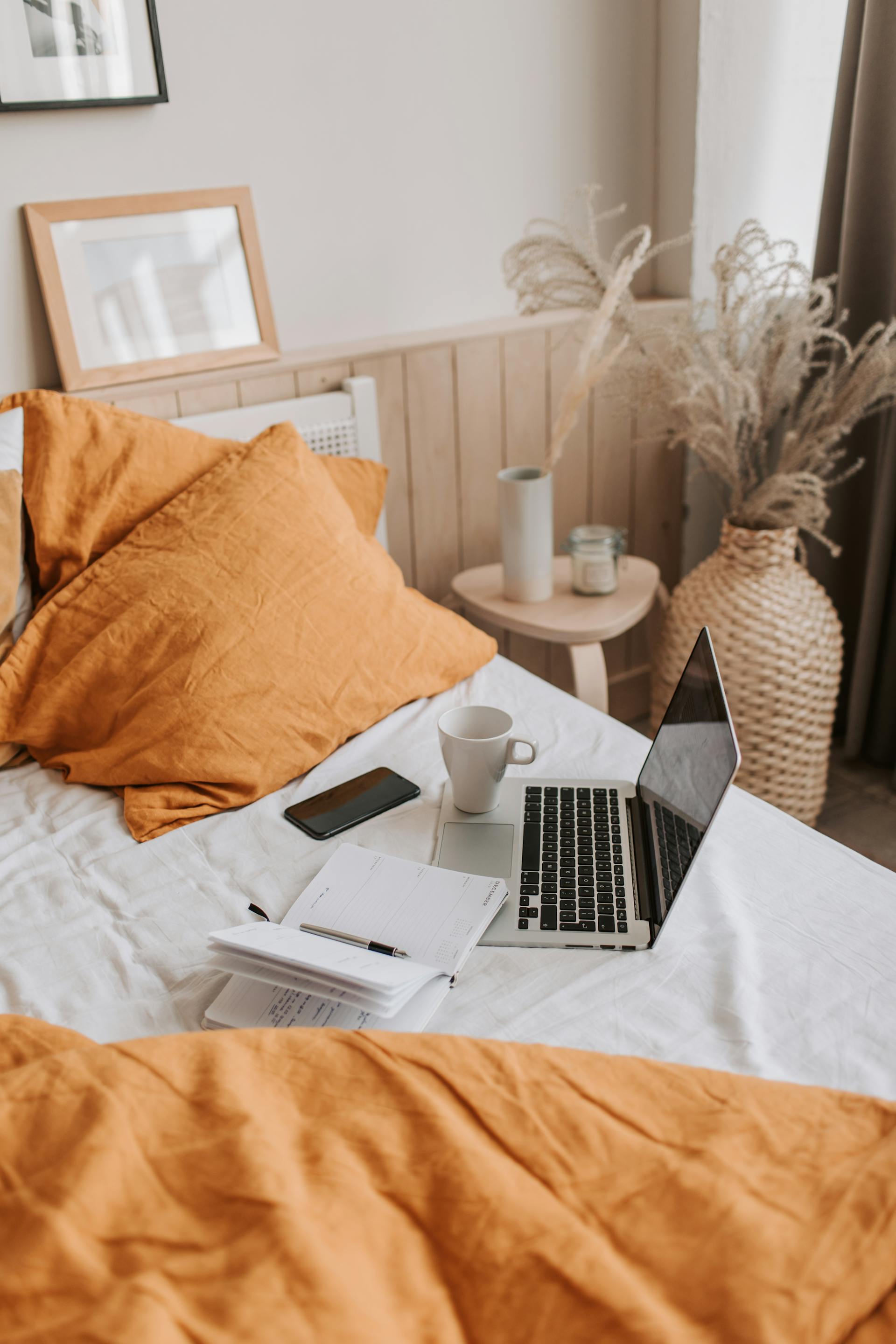A cup of coffee and a laptop on a bed | Source: Pexels