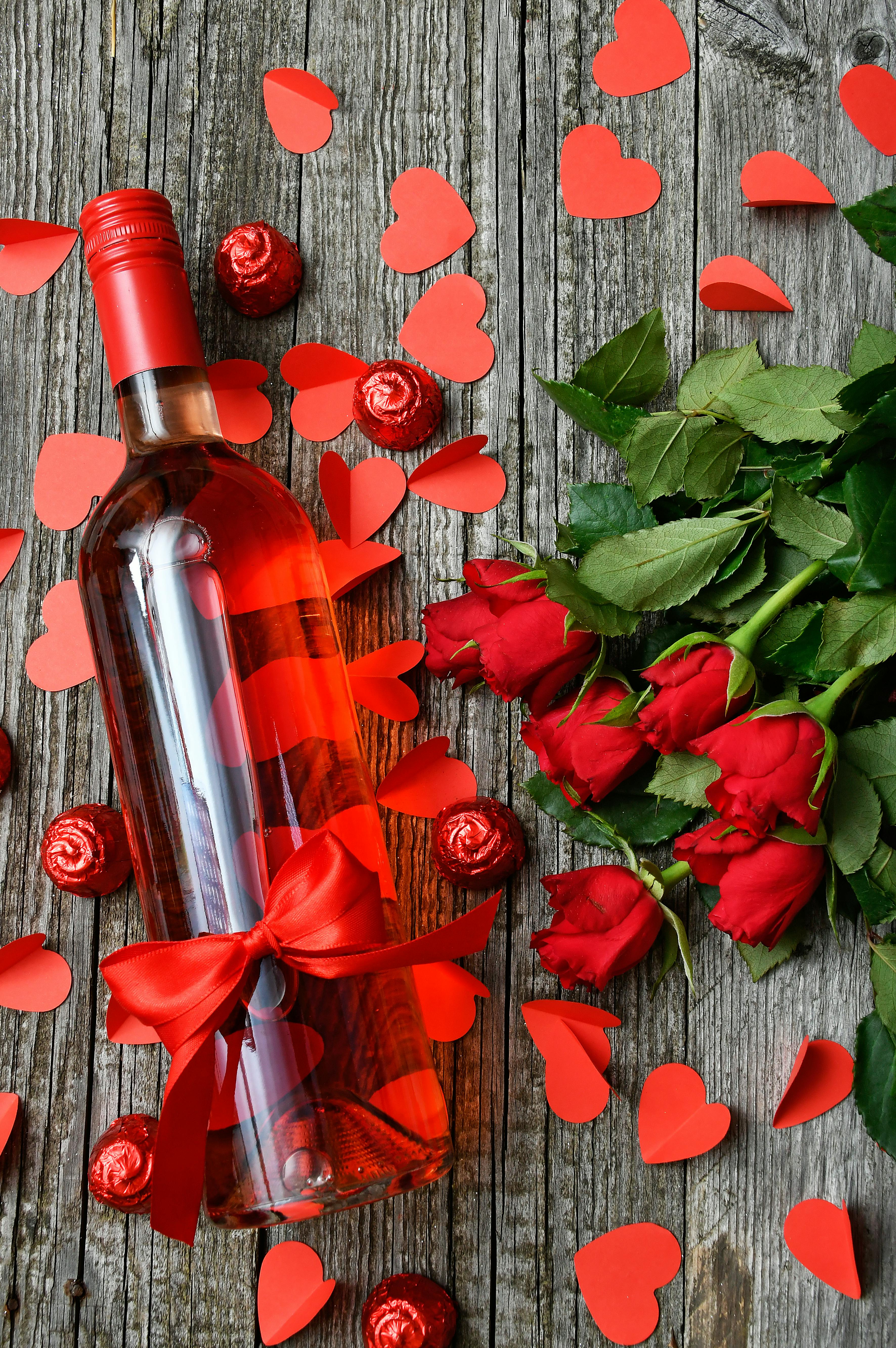 A bottle of wine surrounded by red roses | Source: Pexels