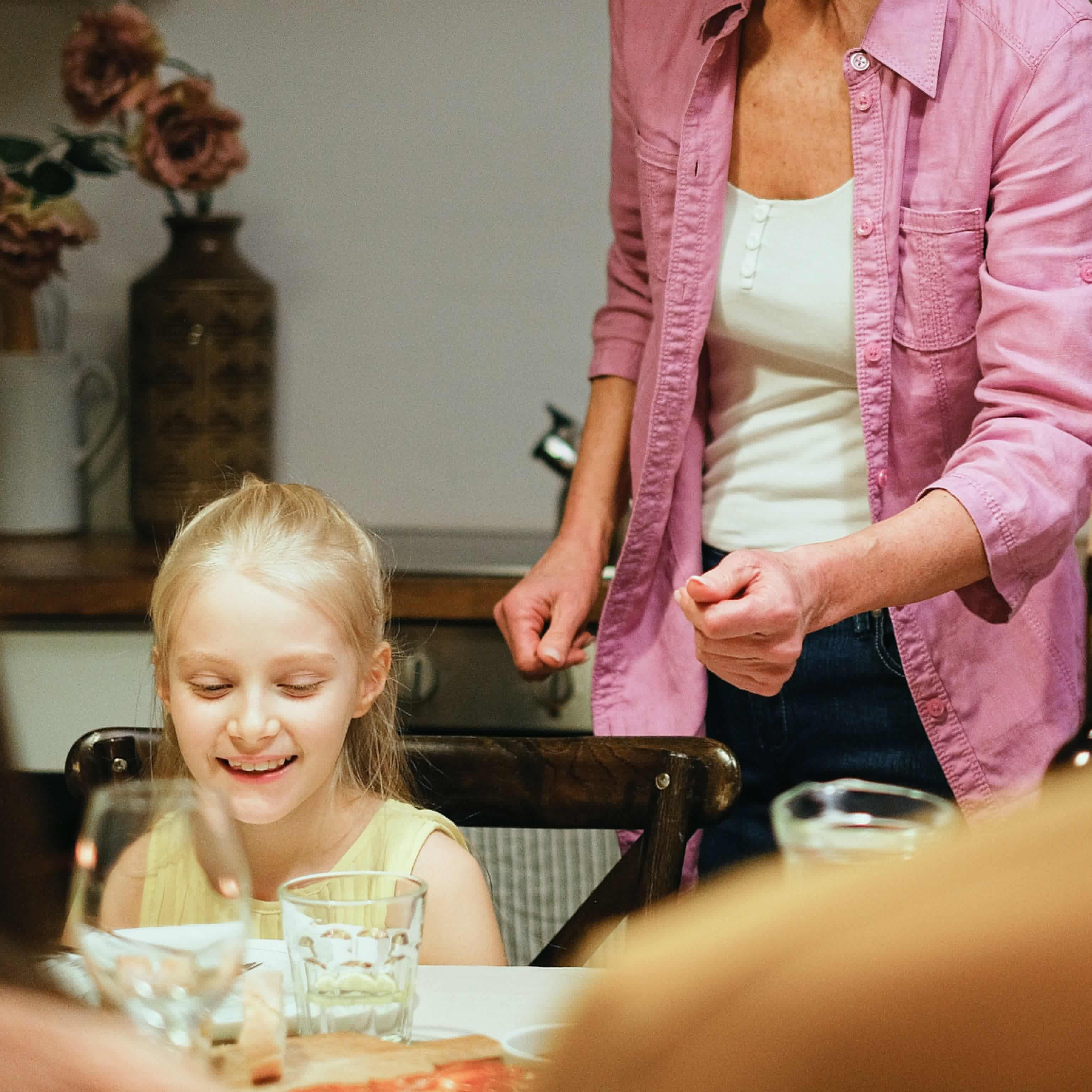 A woman setting dinner for children at a table | Source: Pexels