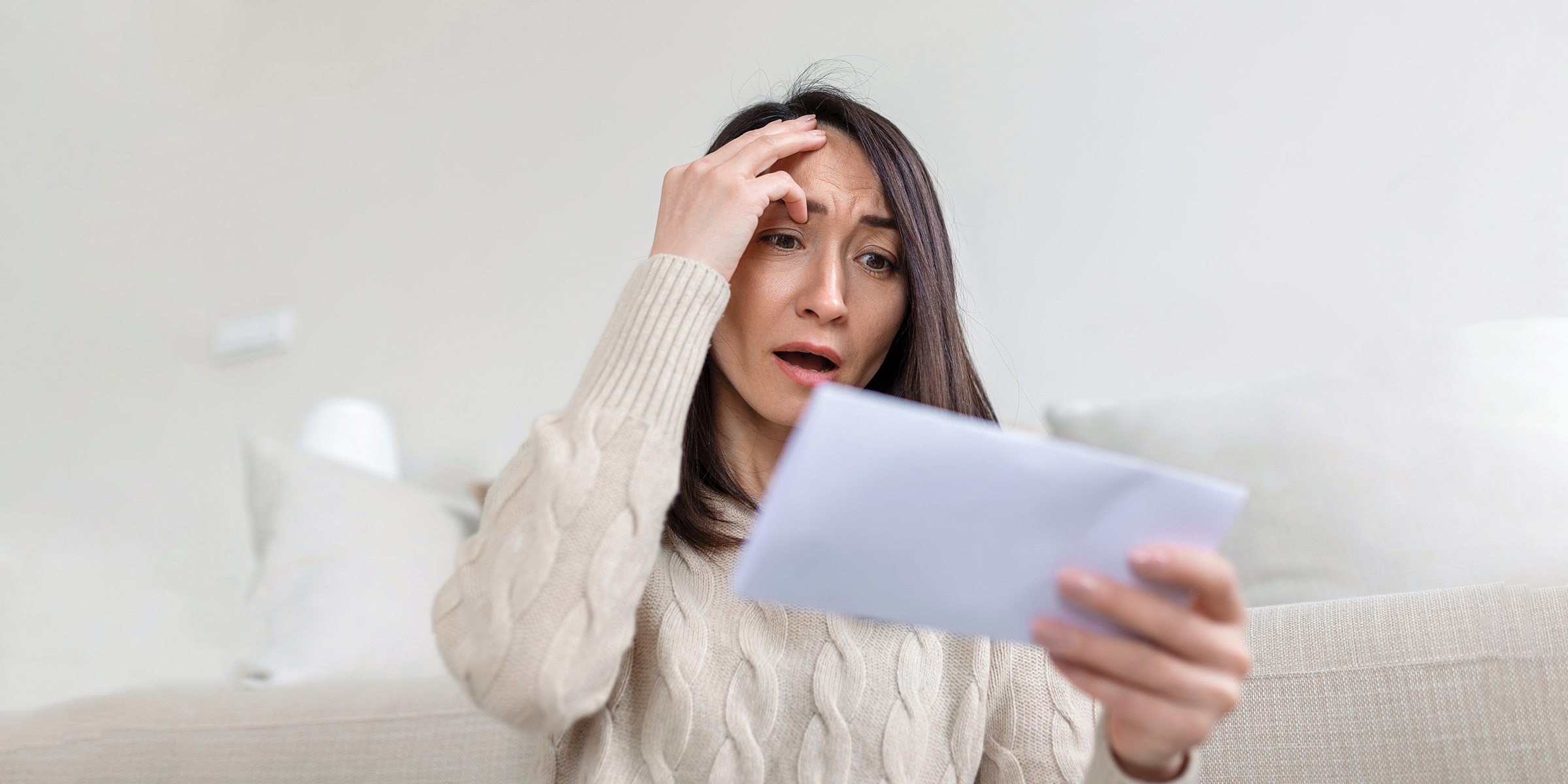 A woman staring at an envelope in shock | Source: Shutterstock