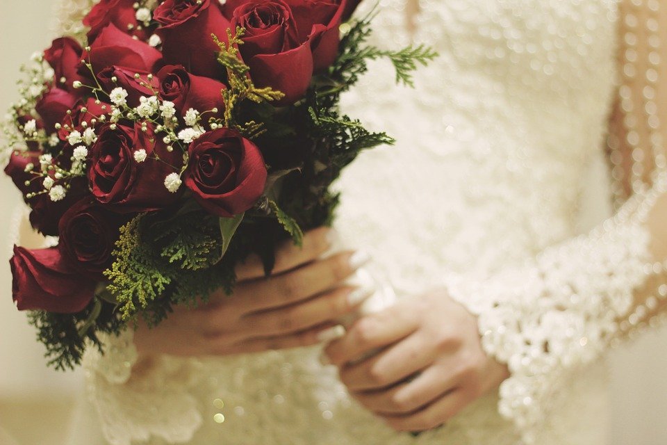 Bride holding red bouquet | Photo: Pixabay