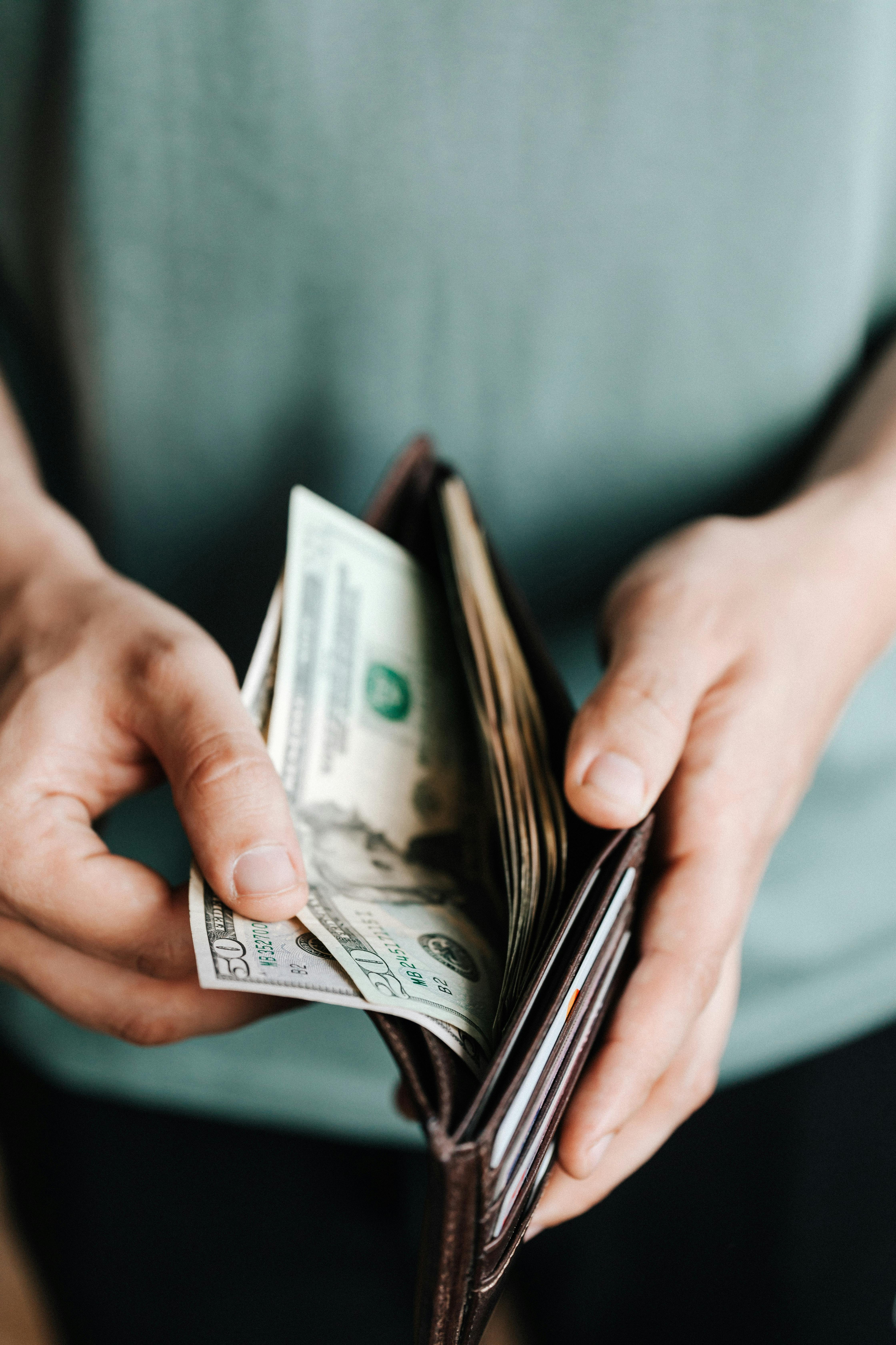 A man taking money out of a wallet | Source: Pexels