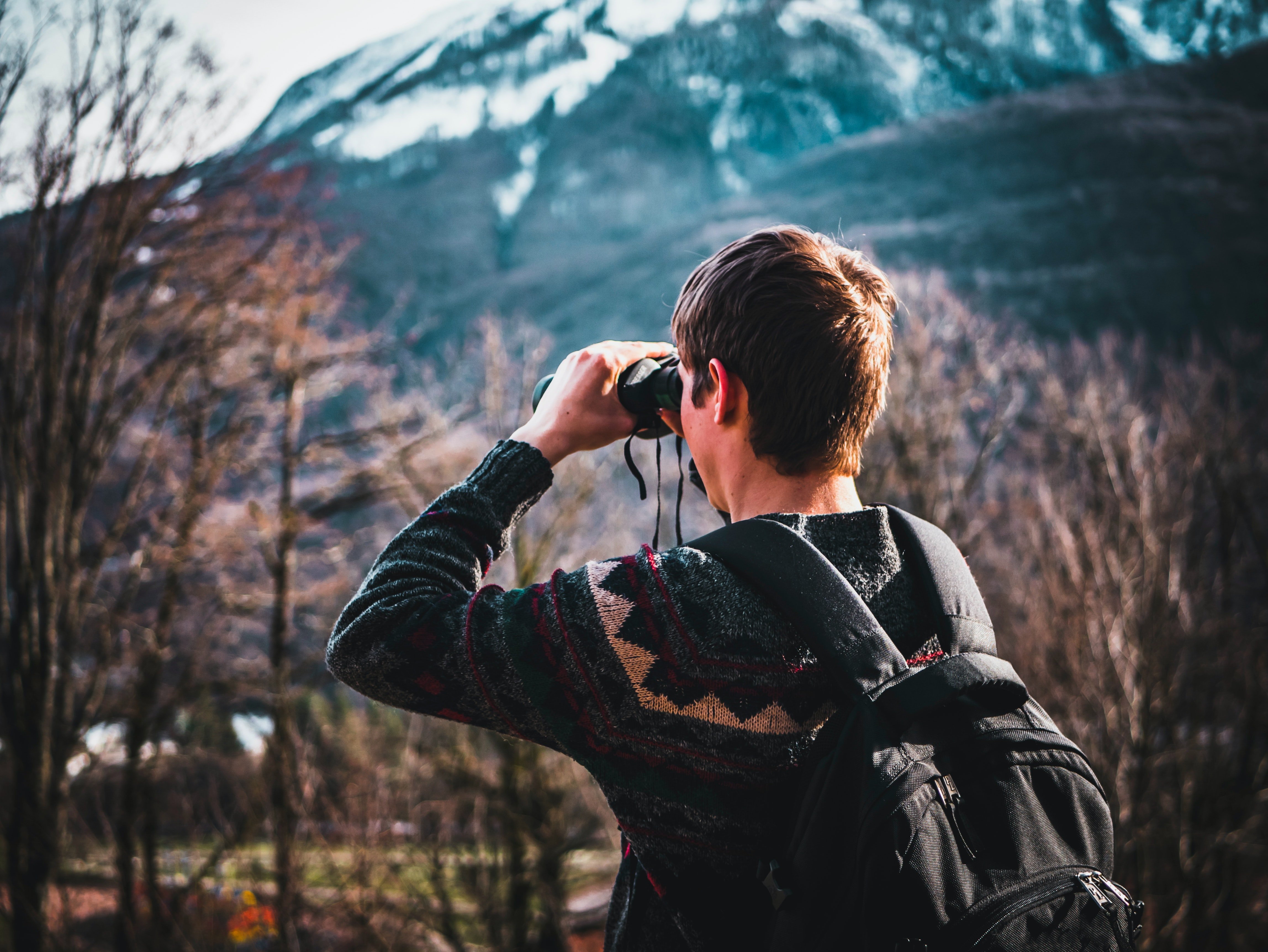Pictured - A man using binoculars near a forest daytime | Source: Pexels 