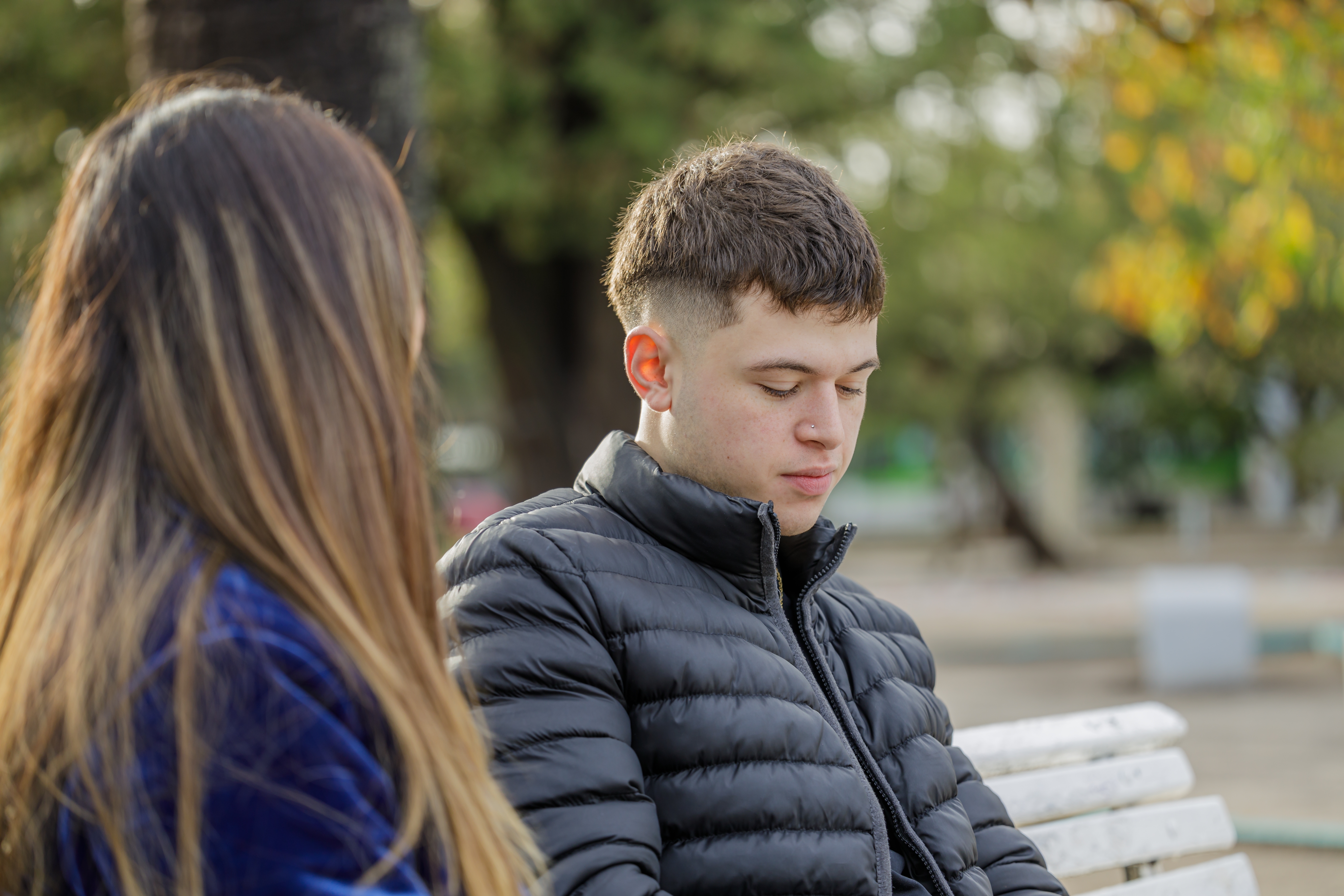 A sad young man telling his story to the woman sitting next to him | Source: Shutterstock