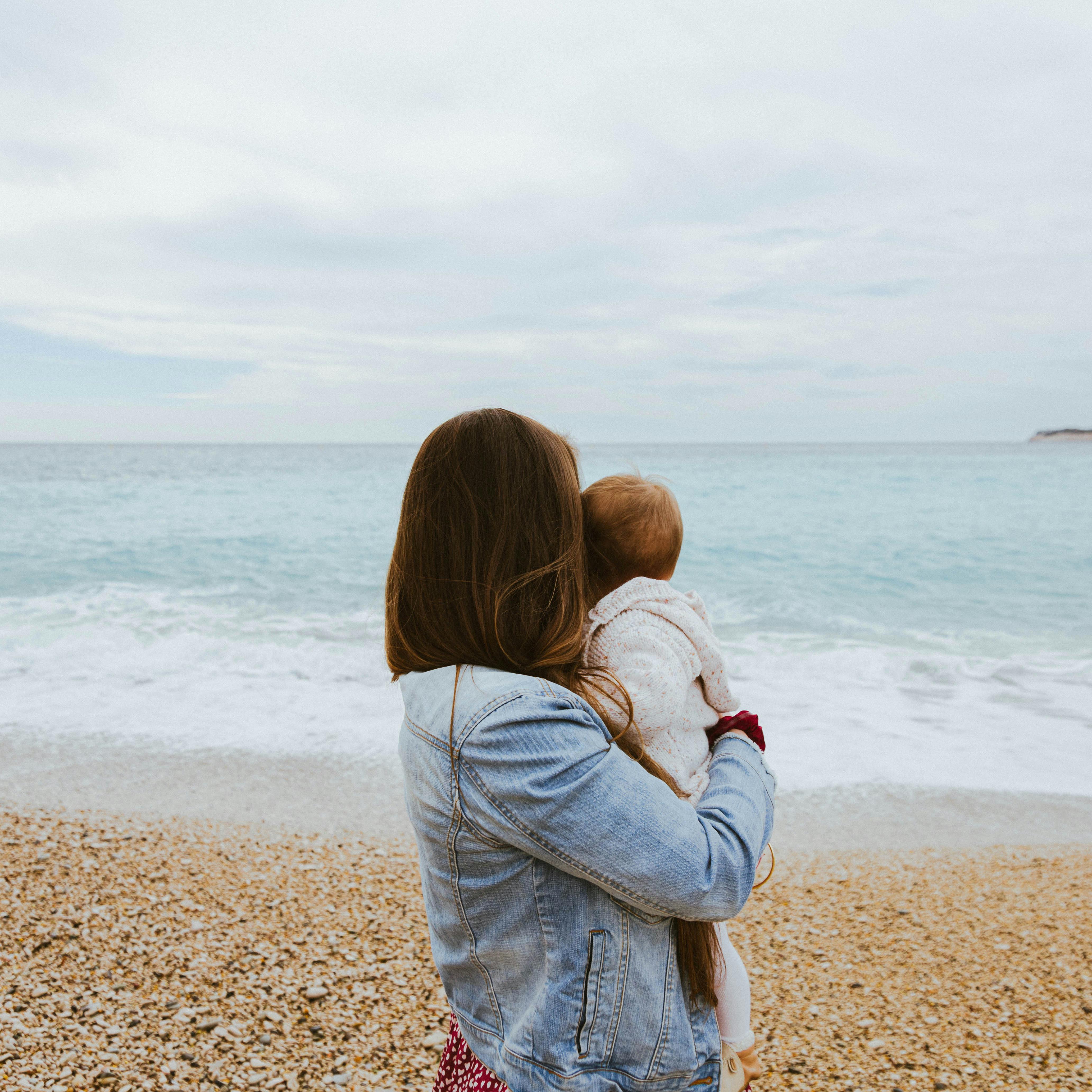 A woman holding her baby at the beach | Source: Pexels