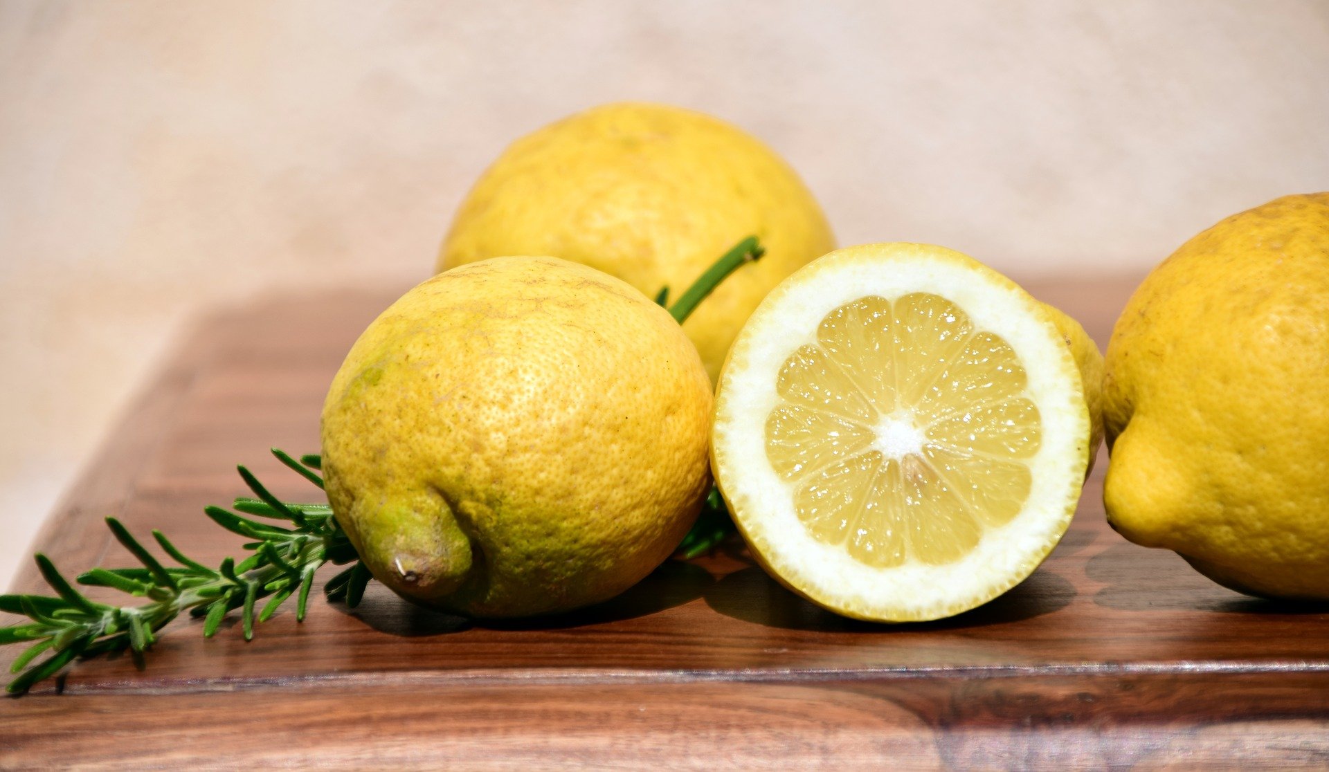 Some lemons with a sprig of rosemary on a chopping board | Photo: Pixabay/Ulrike Leone