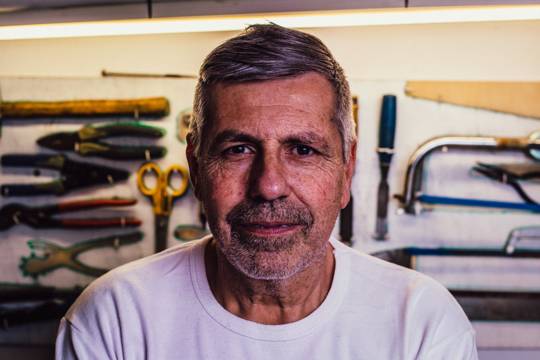 Un hombre mayor con un tablero de herramientas detrás. | Foto: Pexels