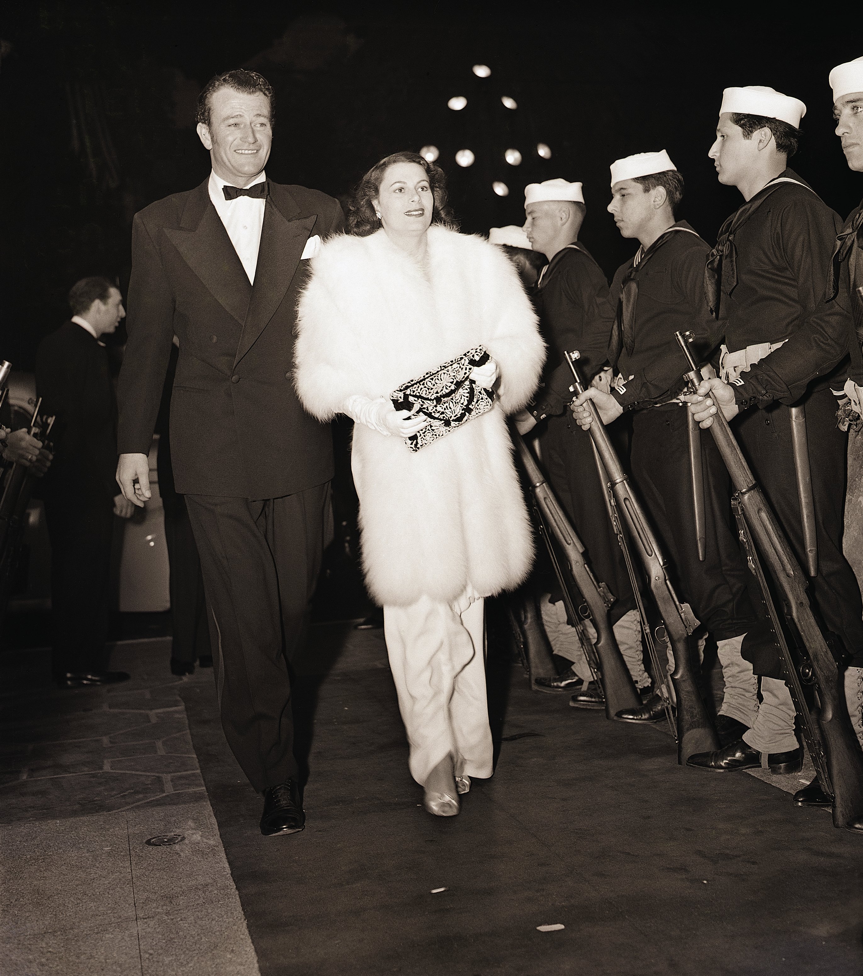John Wayne is pictured with his wife Josephine on their arrival last night at the new Hollywood Theater for the grand premiere of Cecil B. DeMille's latest epic | Source: Getty Images