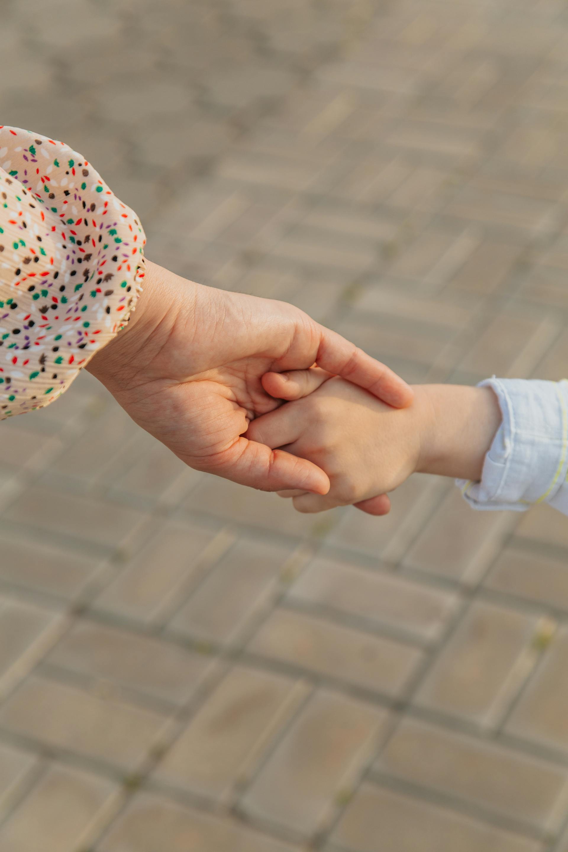 Close-up of a woman holding a little child's hand | Source: Pexels