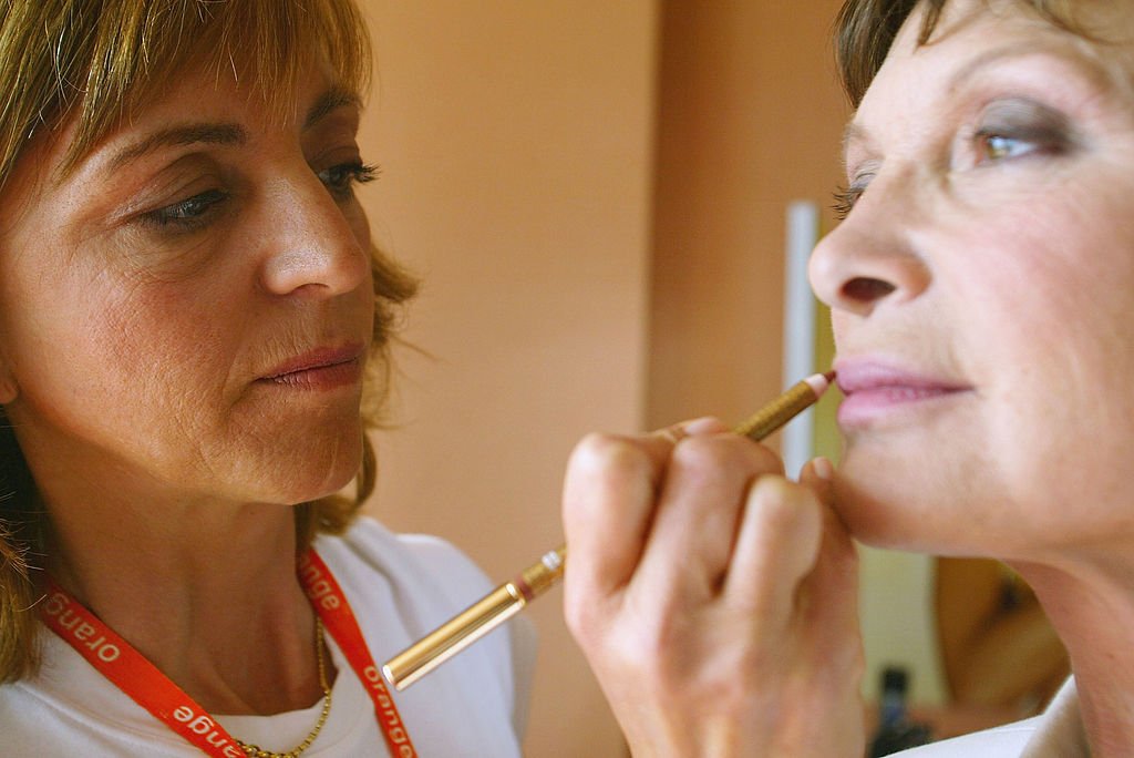Une coiffeuse en train d'appliquer le crayon à lèvres. | Photo : Getty Images
