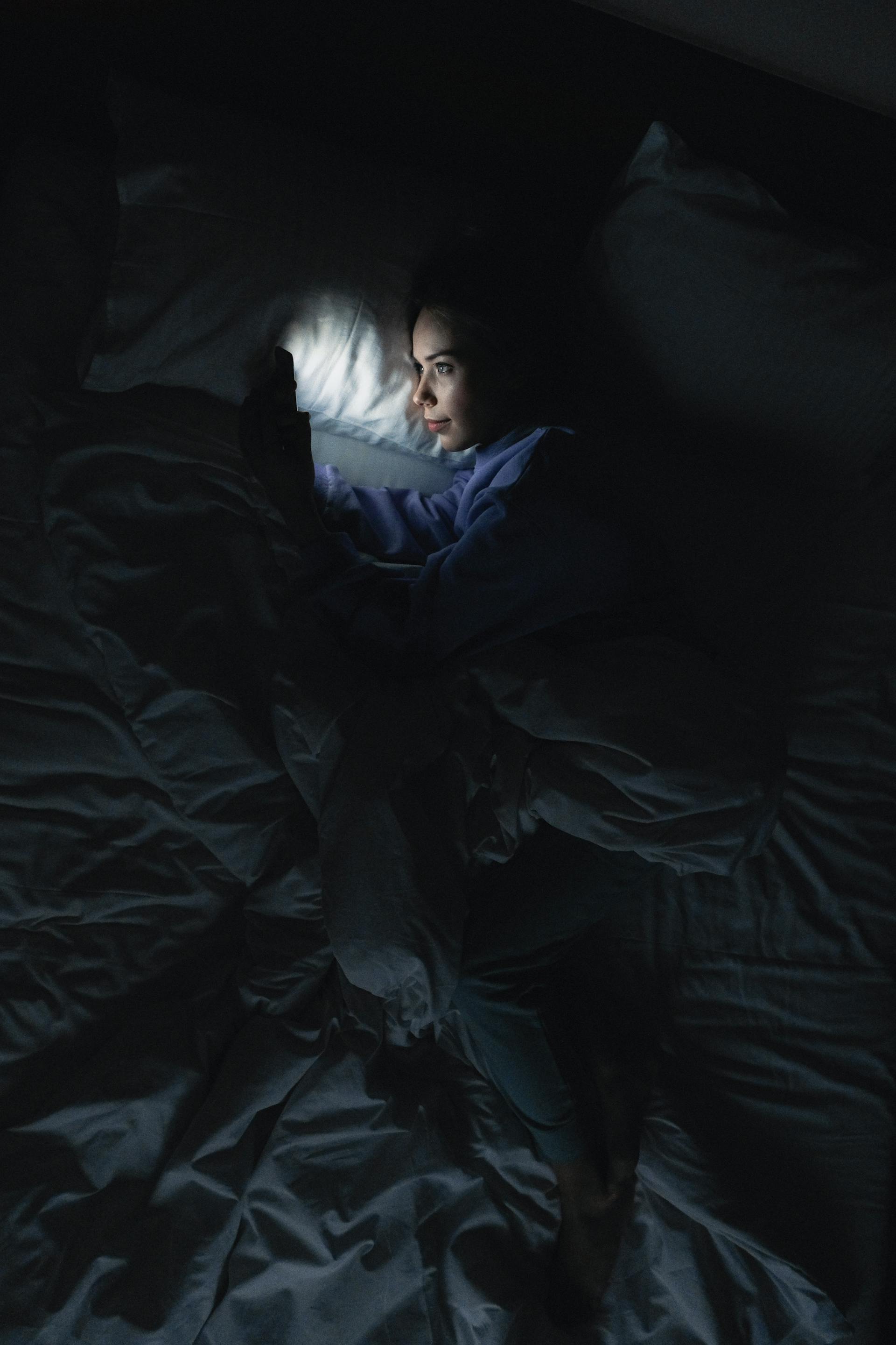 A woman using her phone in bed | Source: Pexels