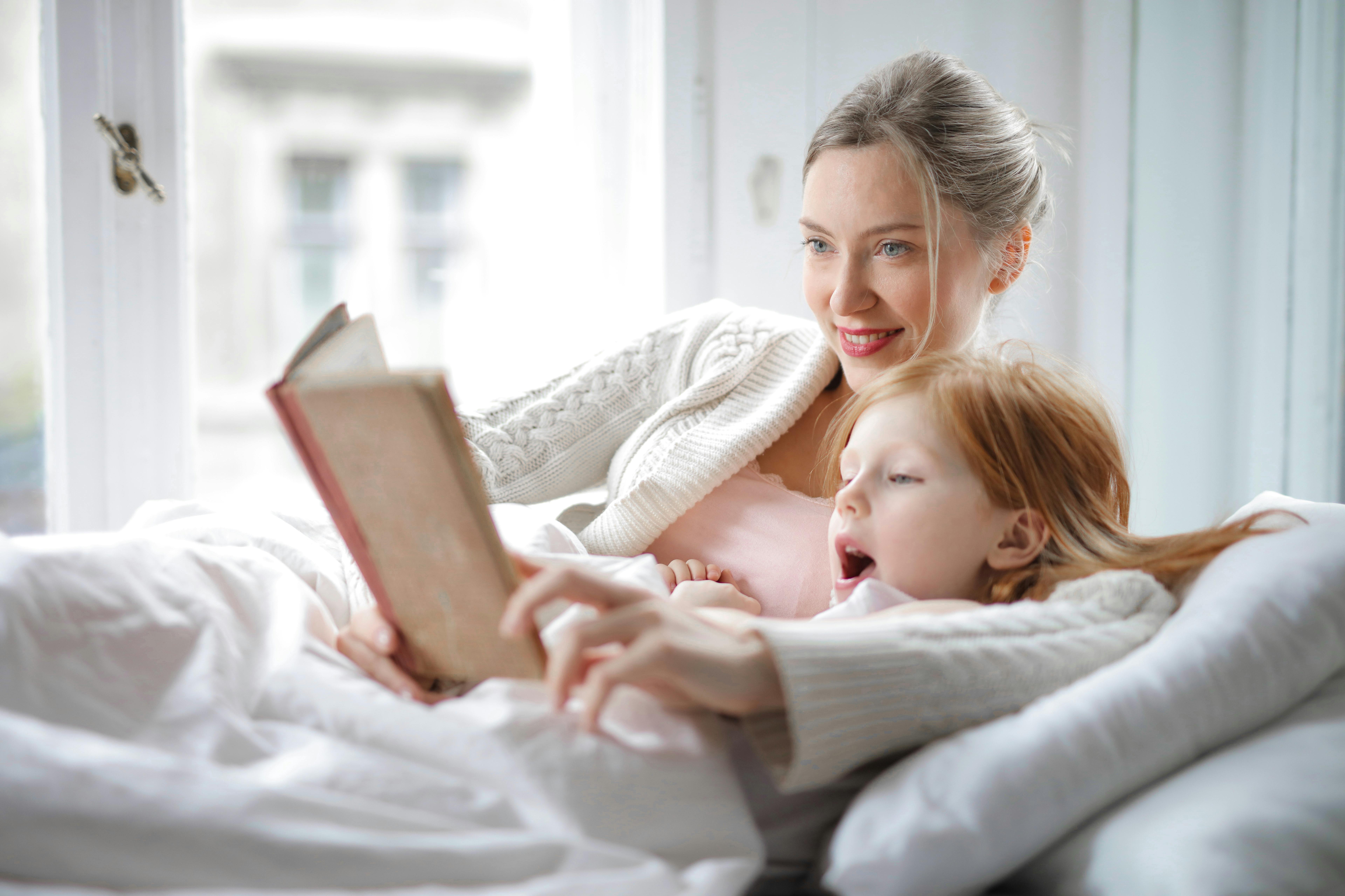 A happy woman and daughter reading a story | Source: Pexels