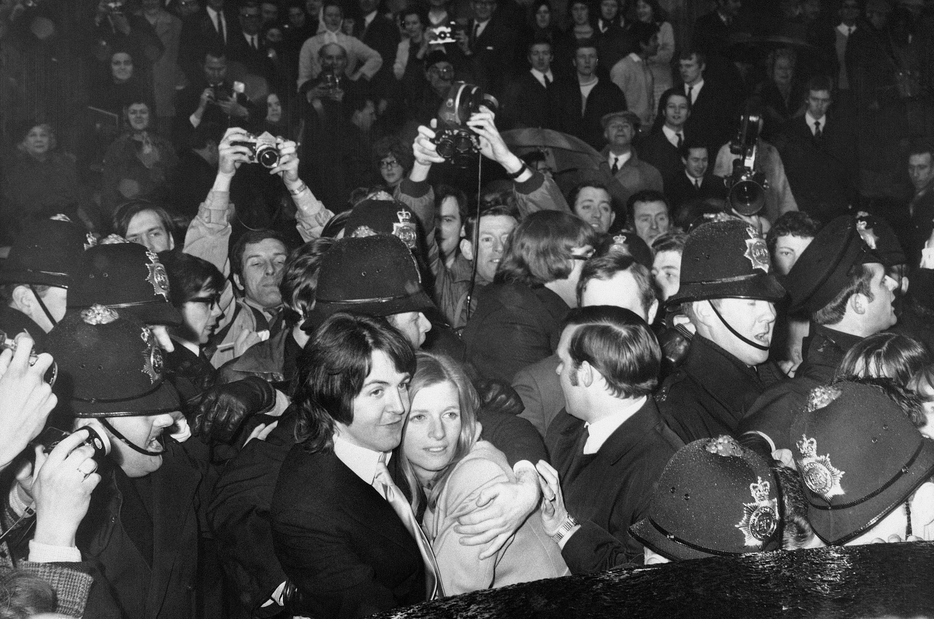 Police officers surrounding Paul McCartney and new wife Linda McCartney as they make their way through fans following their marriage in London | Source: Getty Images