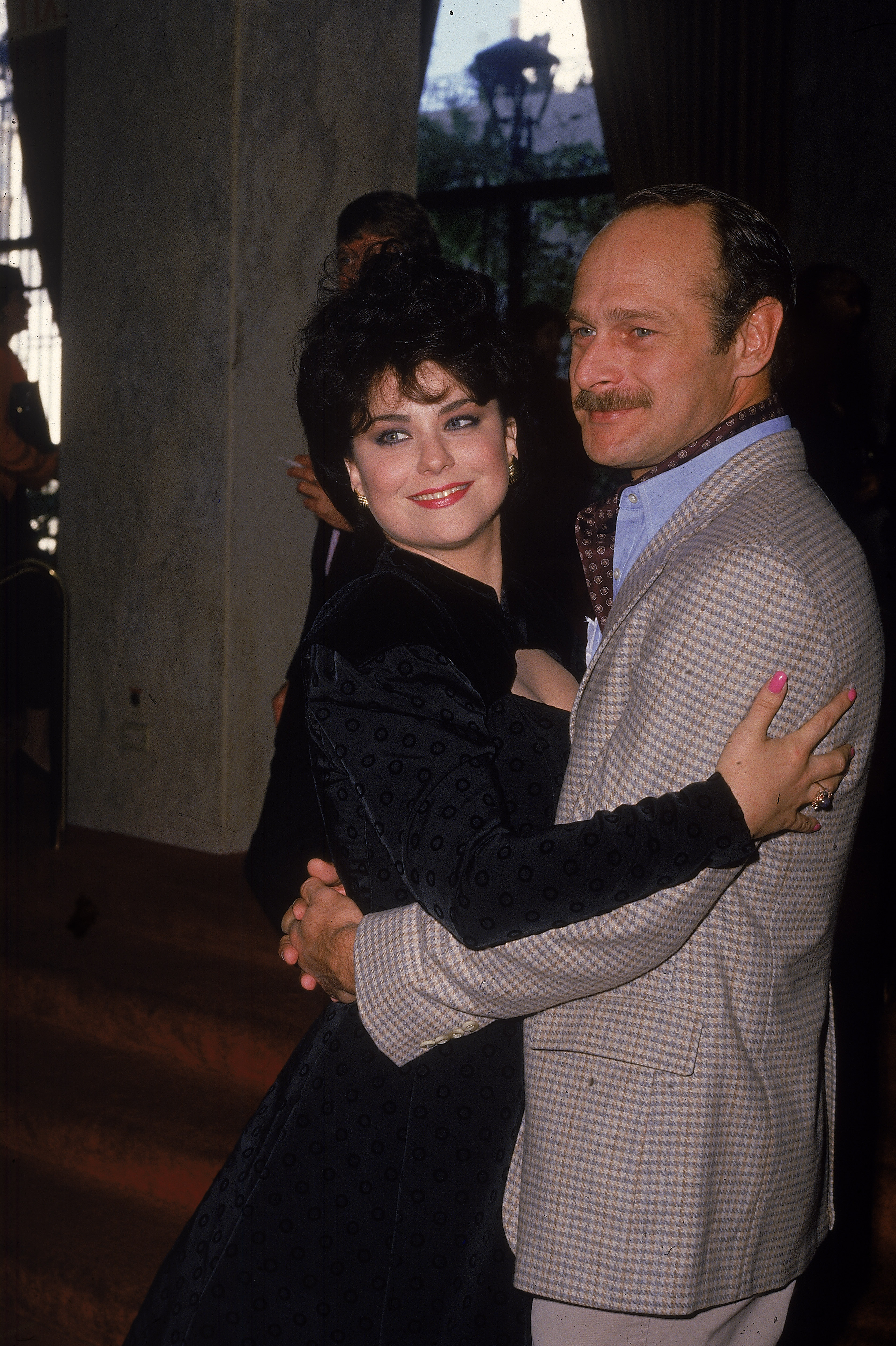 American actors Delta Burke and Gerald McRaney pose hugging as they arrive at the Golden Apple Awards, held at the Beverly Wilshire Hotel, Beverly Hills, California, December 13, 1987. | Source: Getty Images
