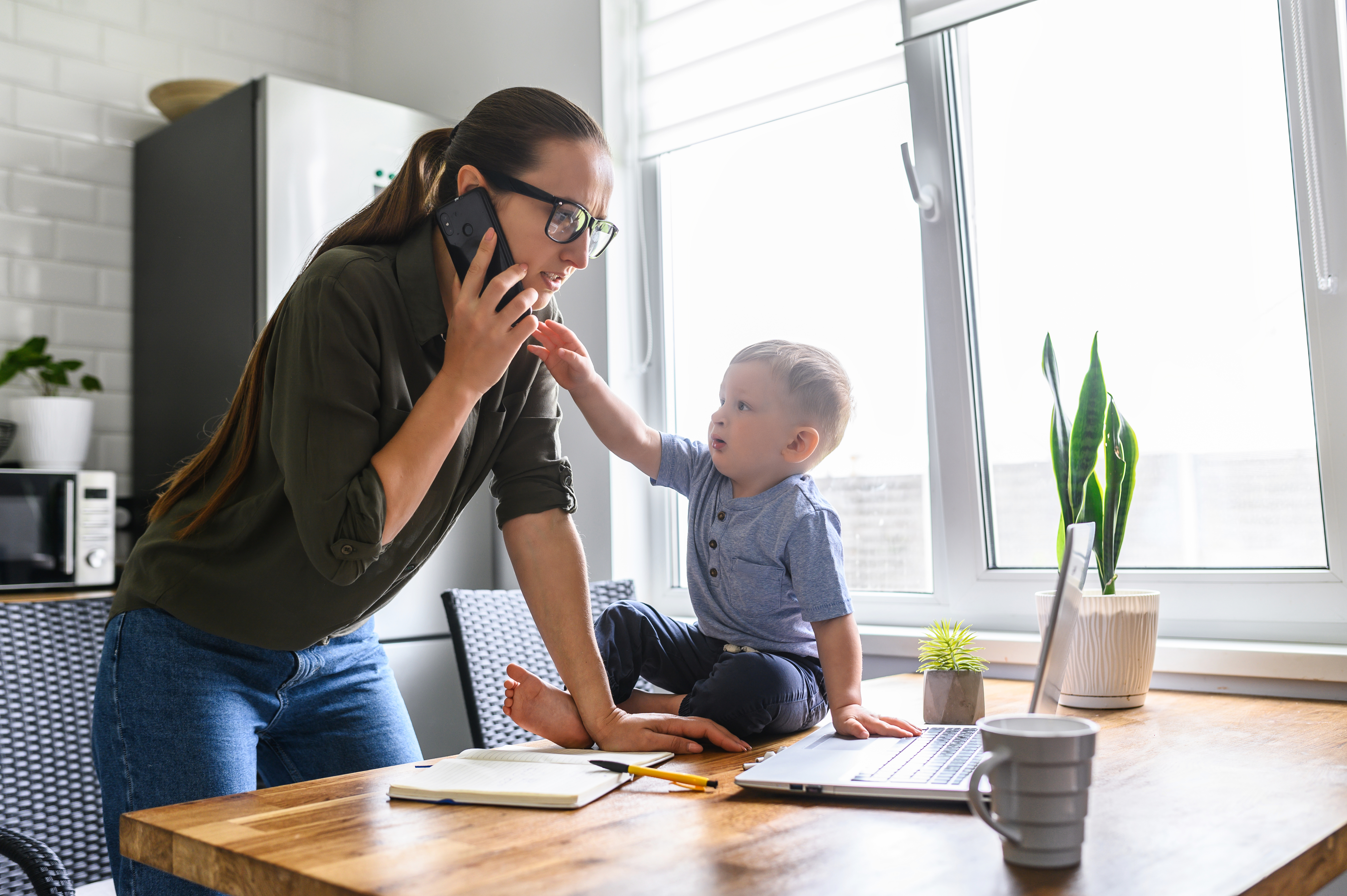 Young mother on the phone as her young son reaches for it | Source: Shutterstock