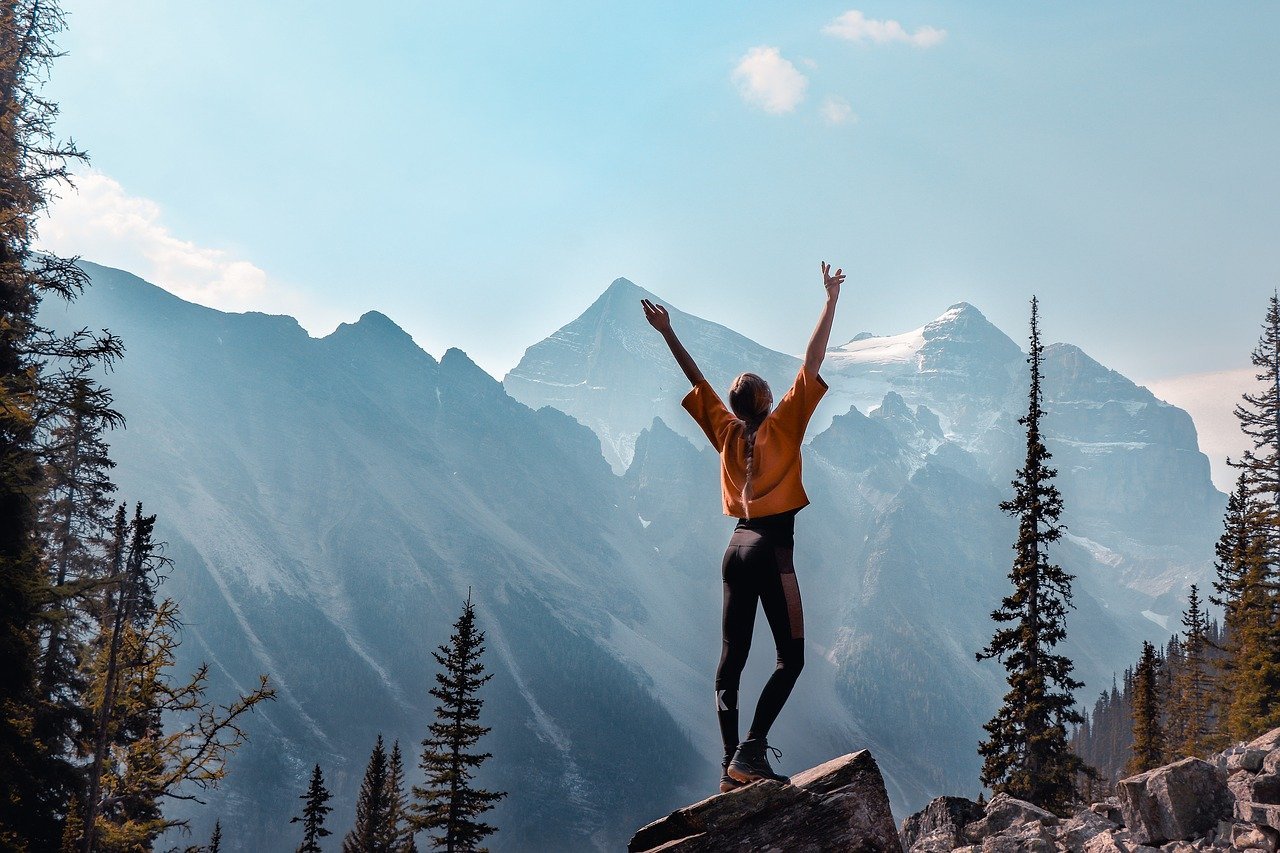 A hiker enjoying herself on top of a mountain. | Image: Pixabay.