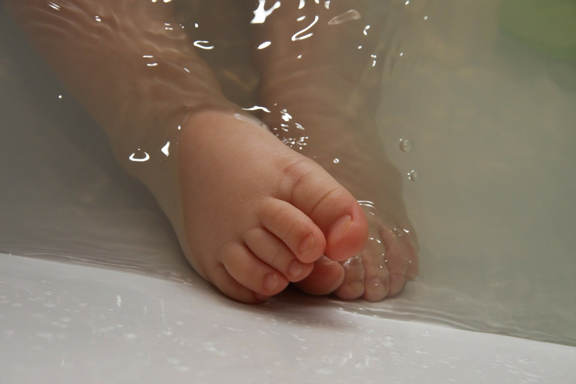 Baby feet in bath filled with water. | Photo: Pixabay/amyelizabethquinn