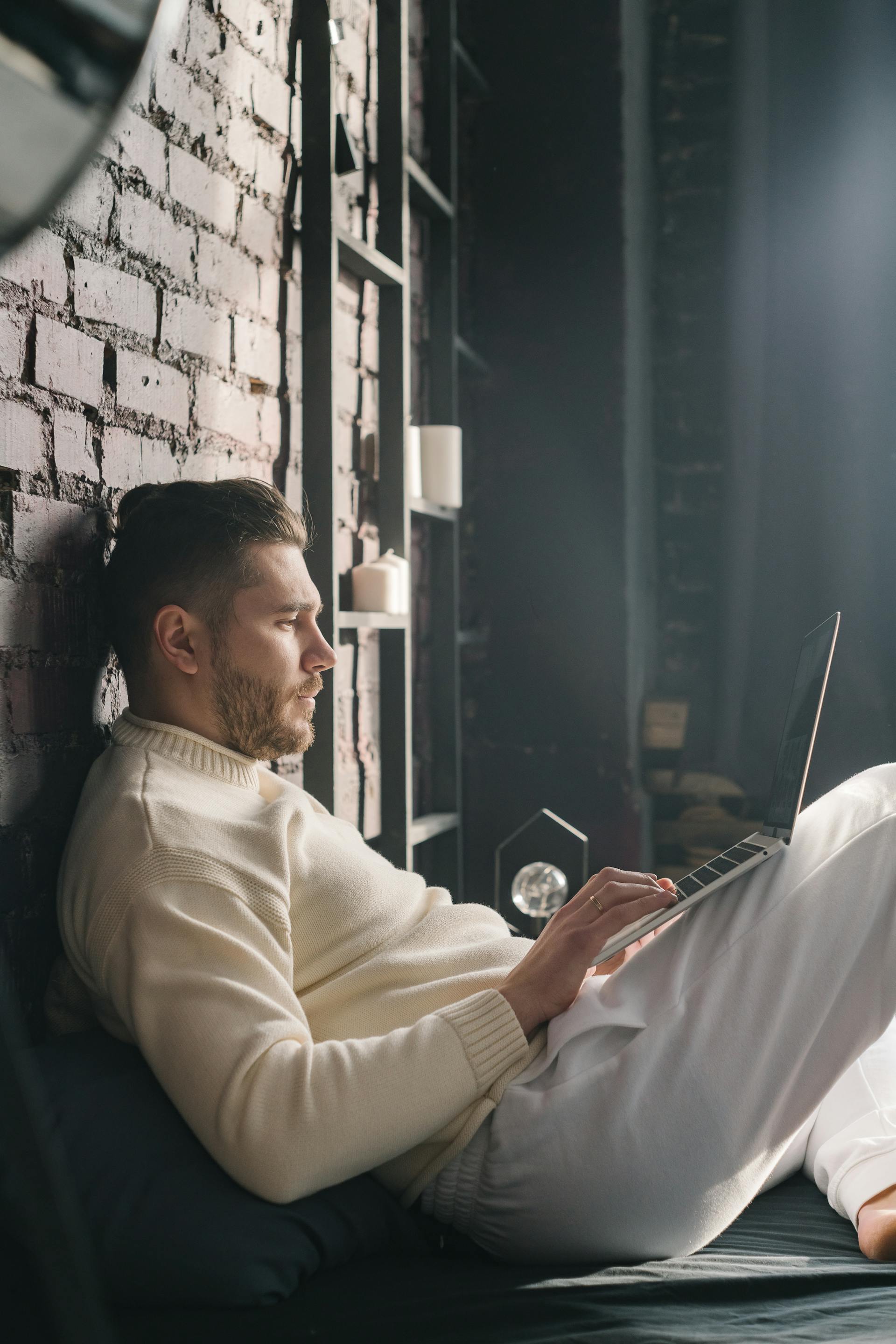 A man sitting on the bed with his laptop | Source: Pexels