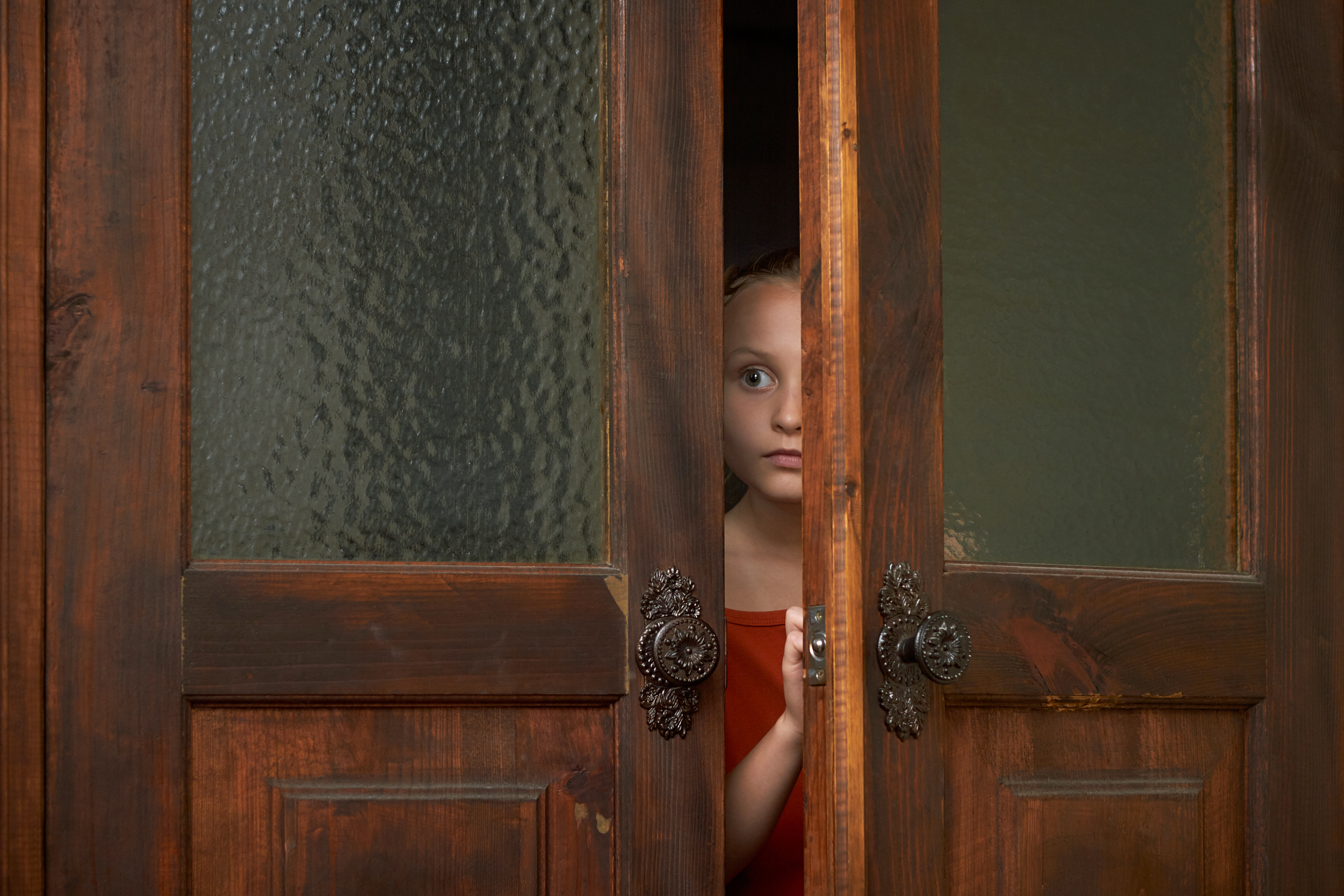 A little scared girl looking through the door slit | Source: Shutterstock