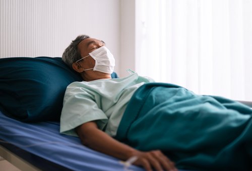 Adulto mayor con tapabocas en una camilla de hospital. | Foto: Shutterstock