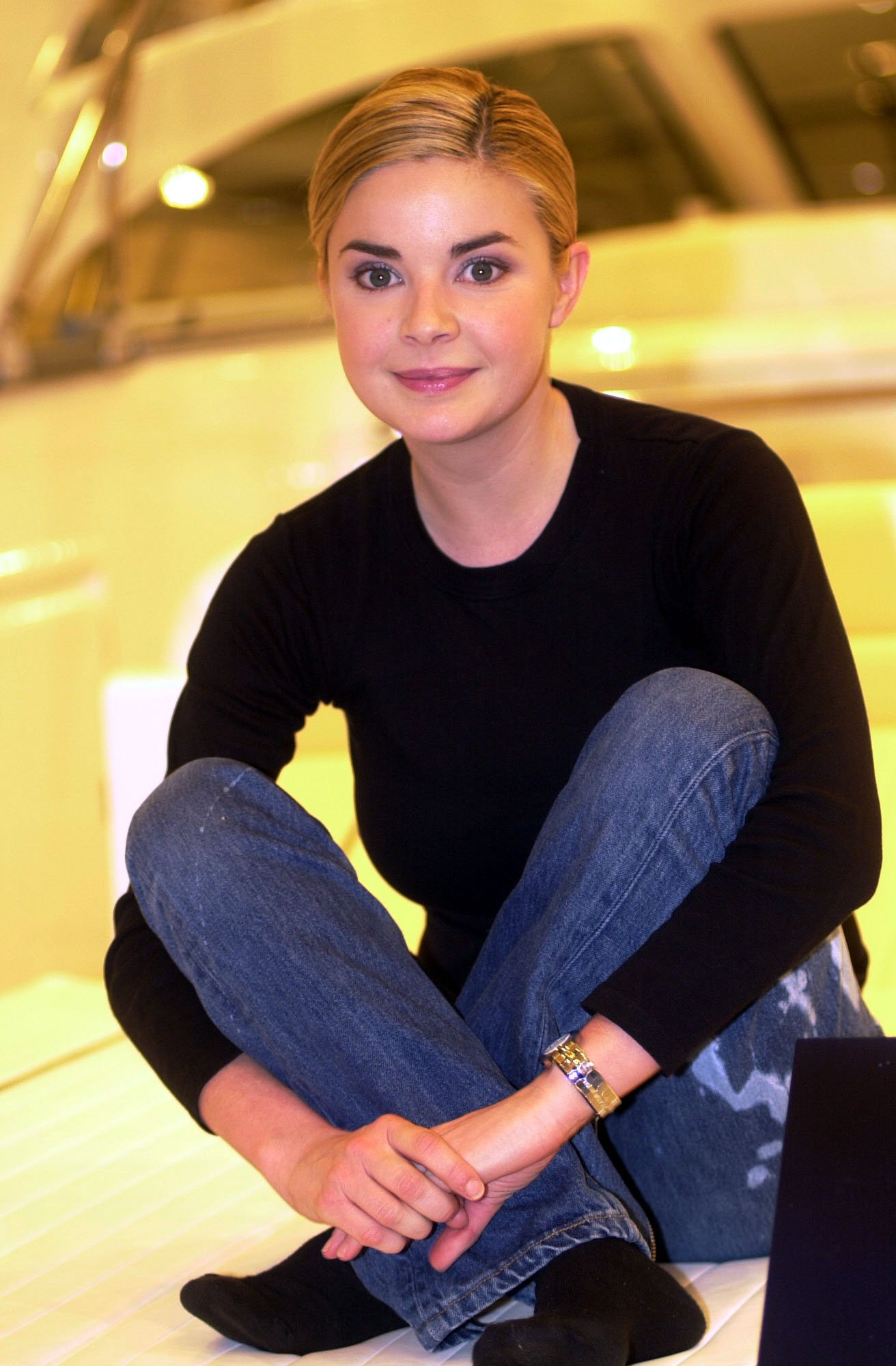 Then–29-year-old, Porter sits cross-legged on the gleaming white deck of a boat exhibit, relaxed and smiling in a fitted black long-sleeve top and loose-fit jeans, her hair cropped very short and pushed neatly back. Pictured at the London Boat Show, Earls Court, January 2001.
