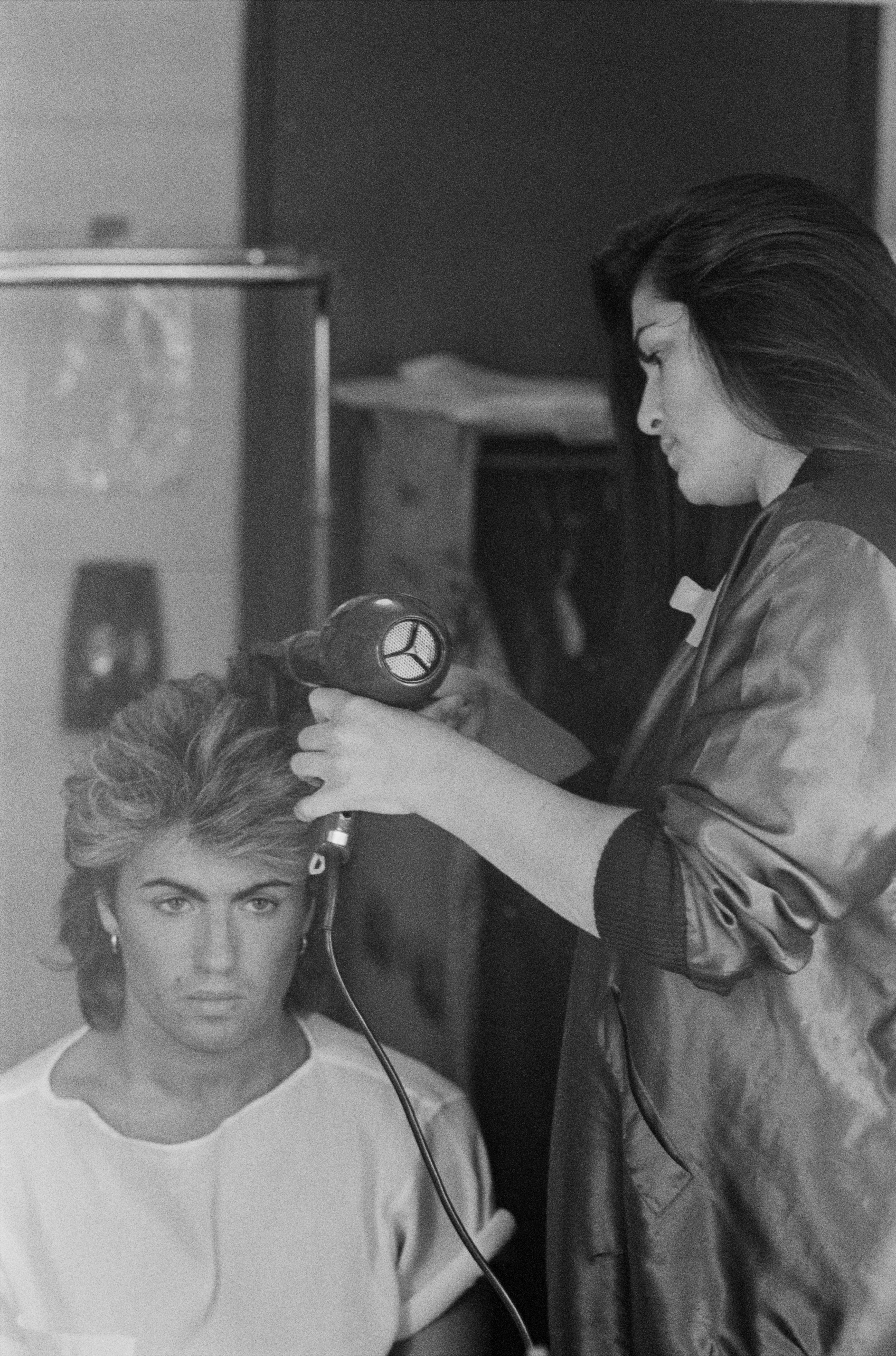 George Michael pictured having his hair done by a stylist backstage on January 1, 1985 in Australia | Source: Getty Images