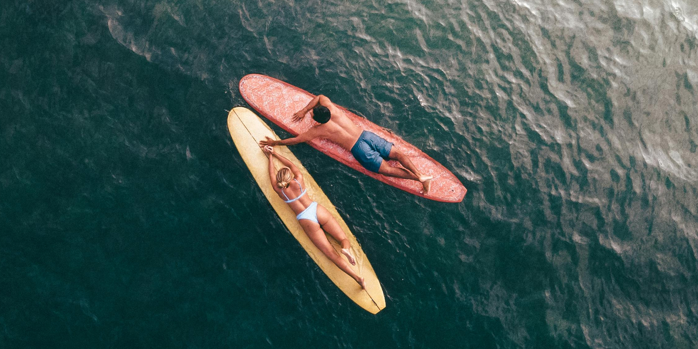 Couple lying on surfboards. | Source: Pexels