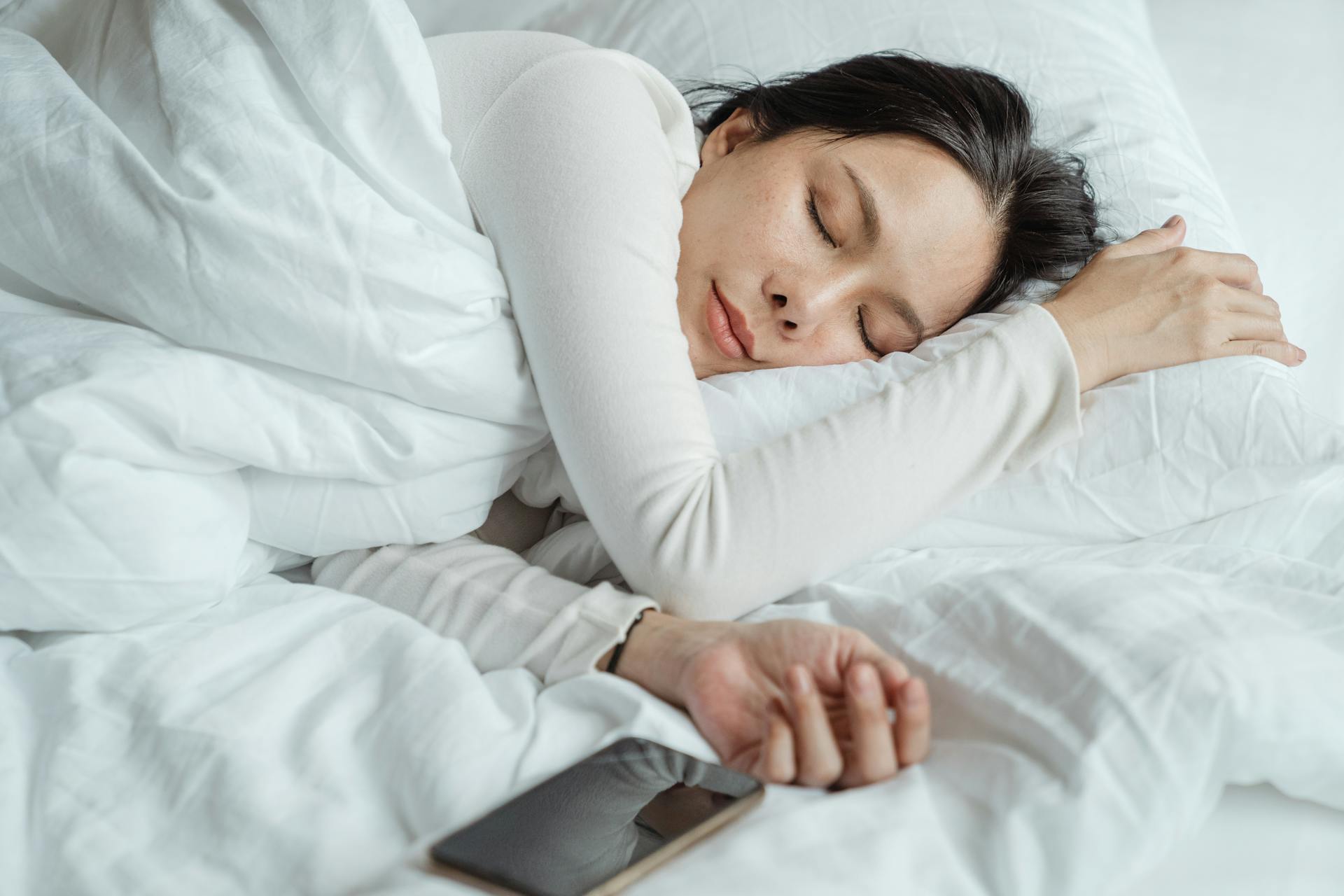 A woman sleeping with her phone next to her | Source: Pexels