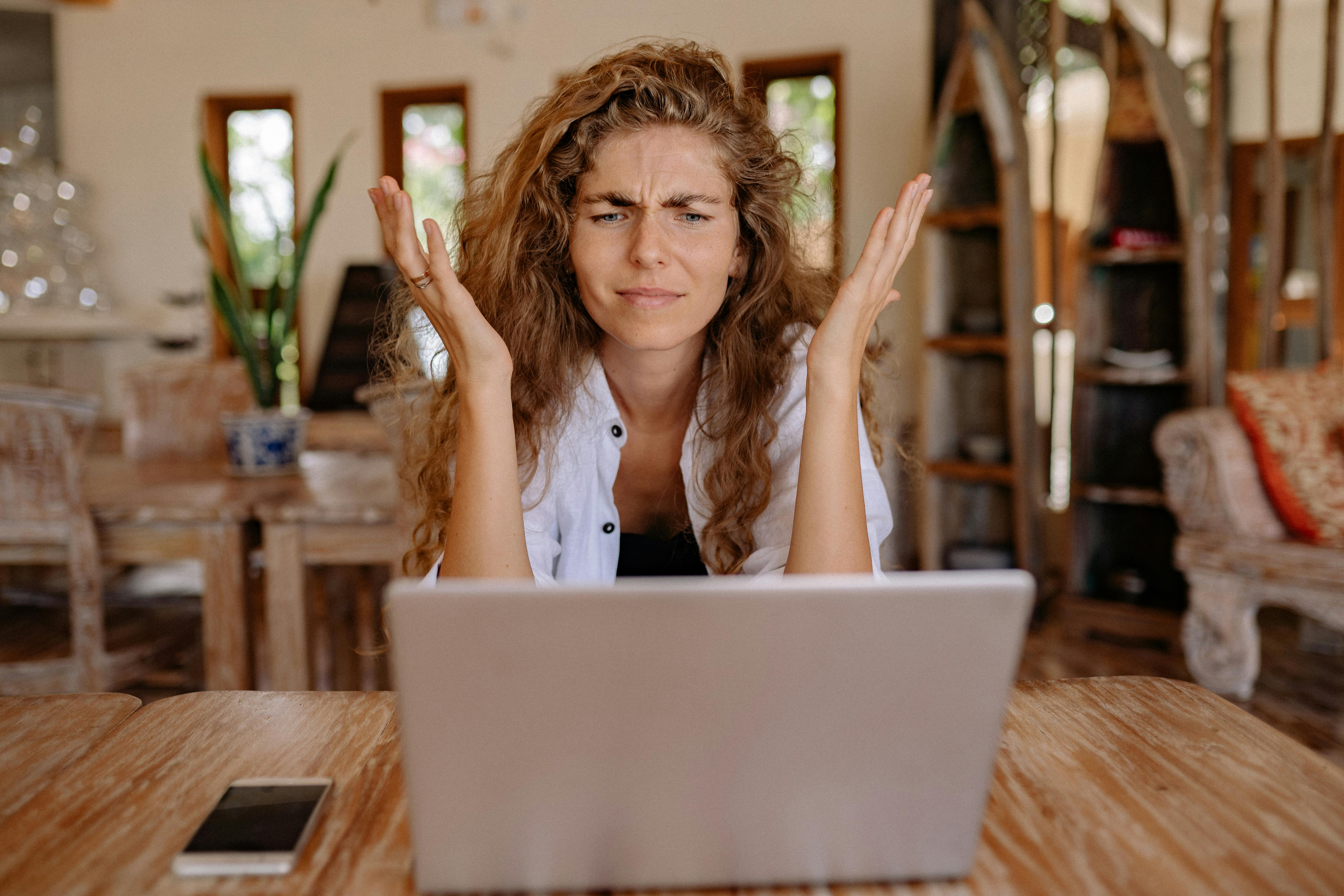 A frustrated woman with her hands up while looking at a laptop screen | Source: Pexels