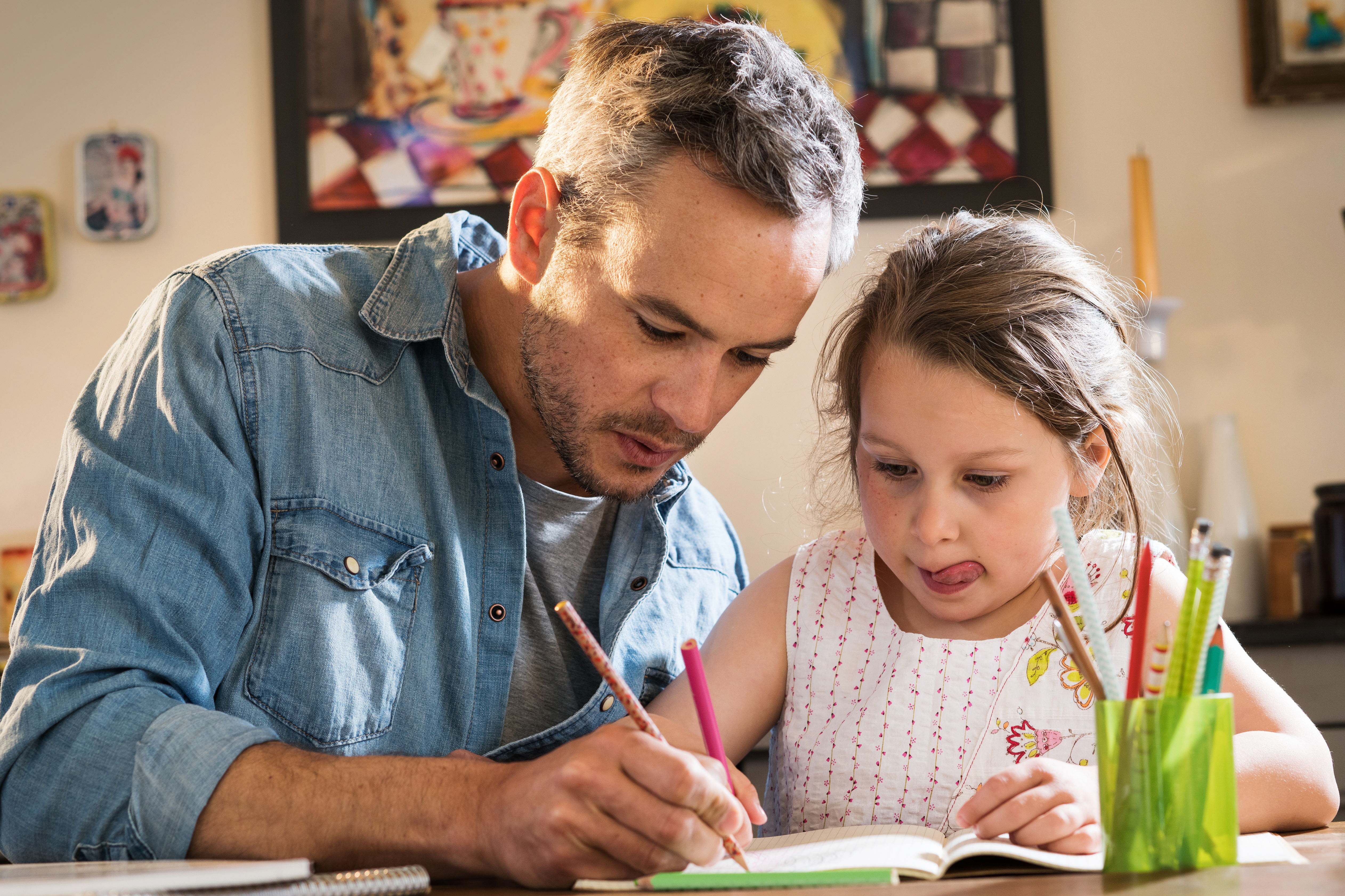 A man helping a child with her homework | Source: Shutterstock