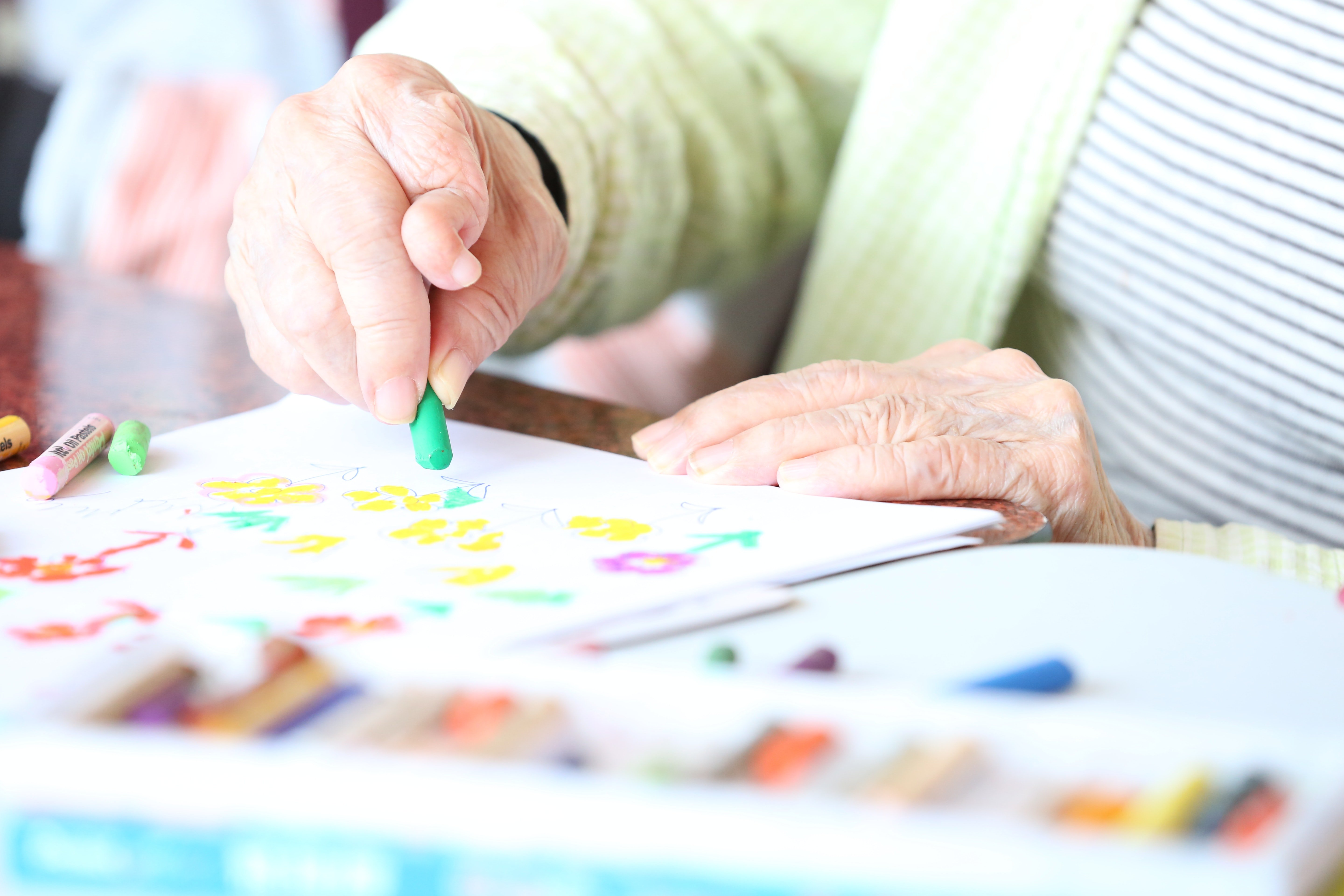 Manos de una persona mayor coloreando un dibujo. | Foto: Pexels