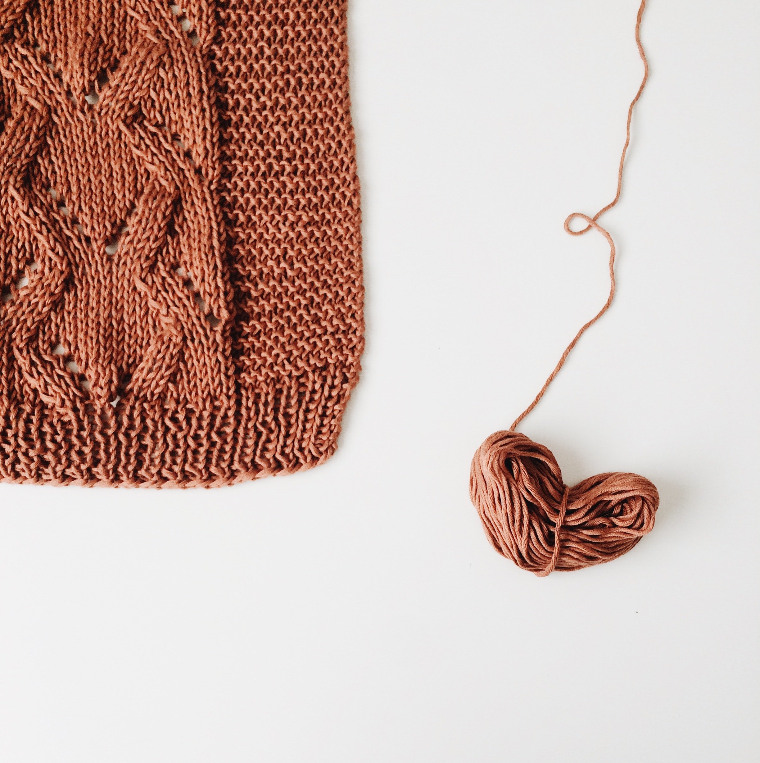 A ball of brown yarn and a portion of a brown knitted sweater | Source: Unsplash