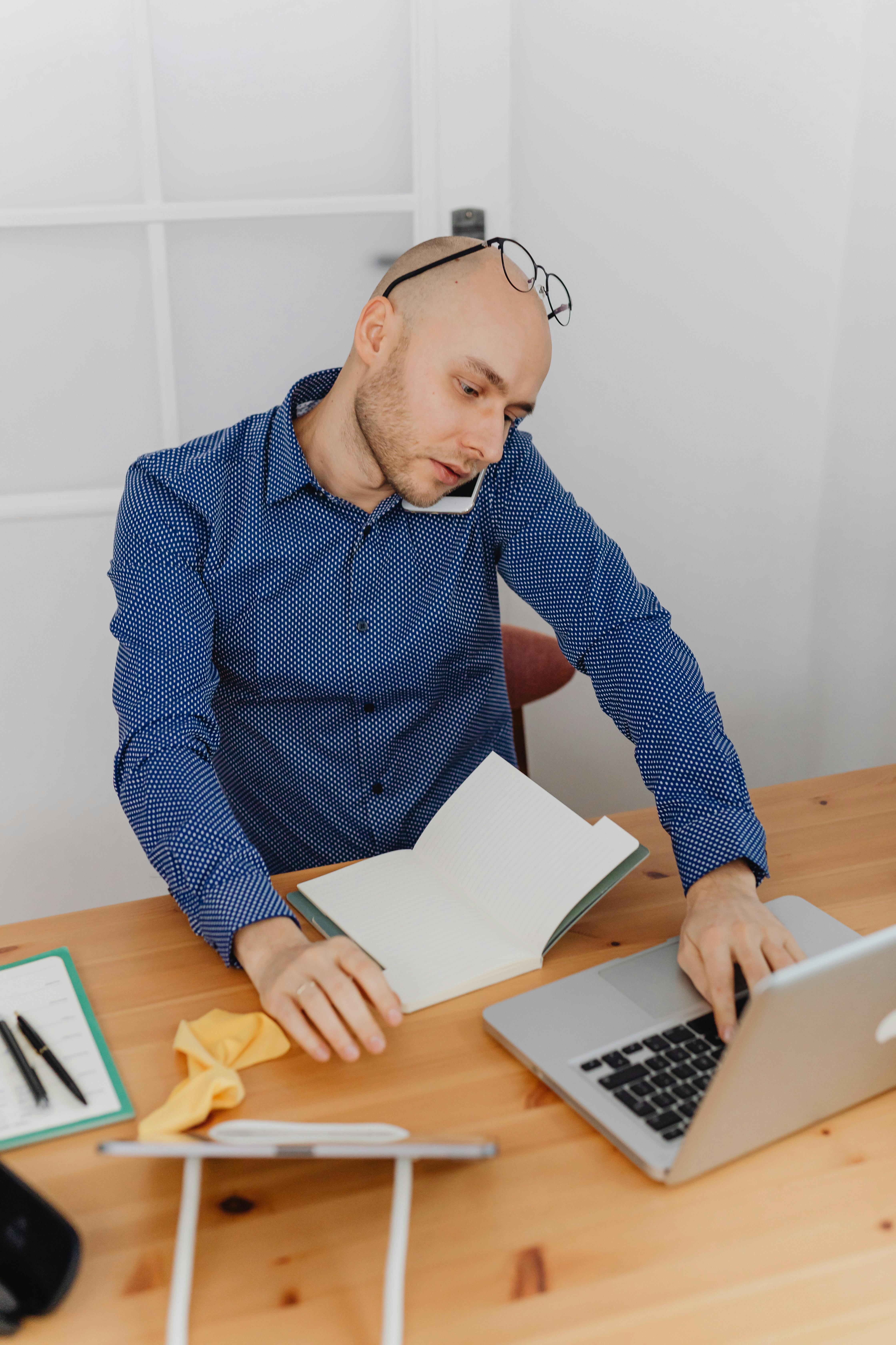 A man talking on his phone and typing | Source: Pexels