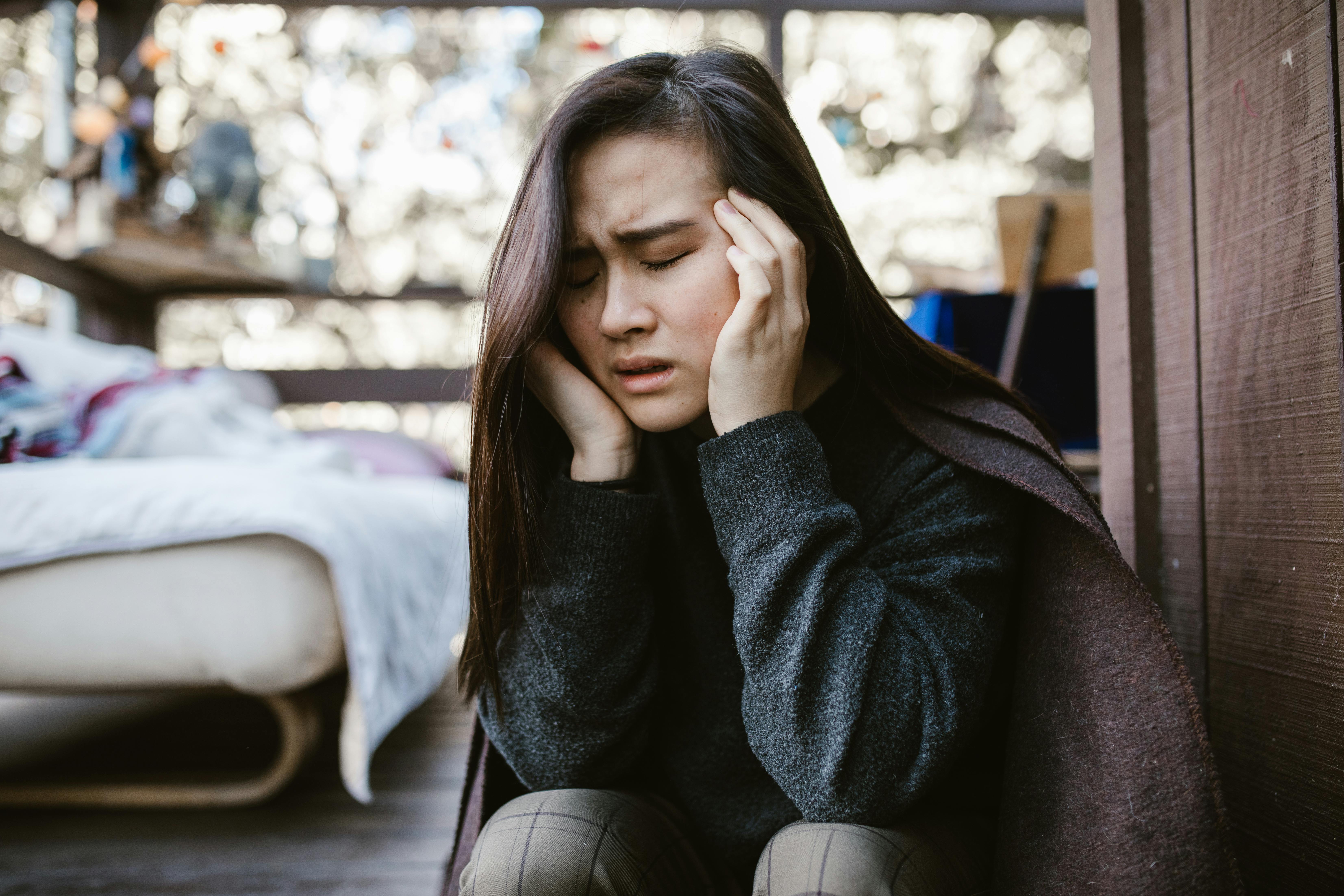 A woman holding her head in pain. | Source: Pexels