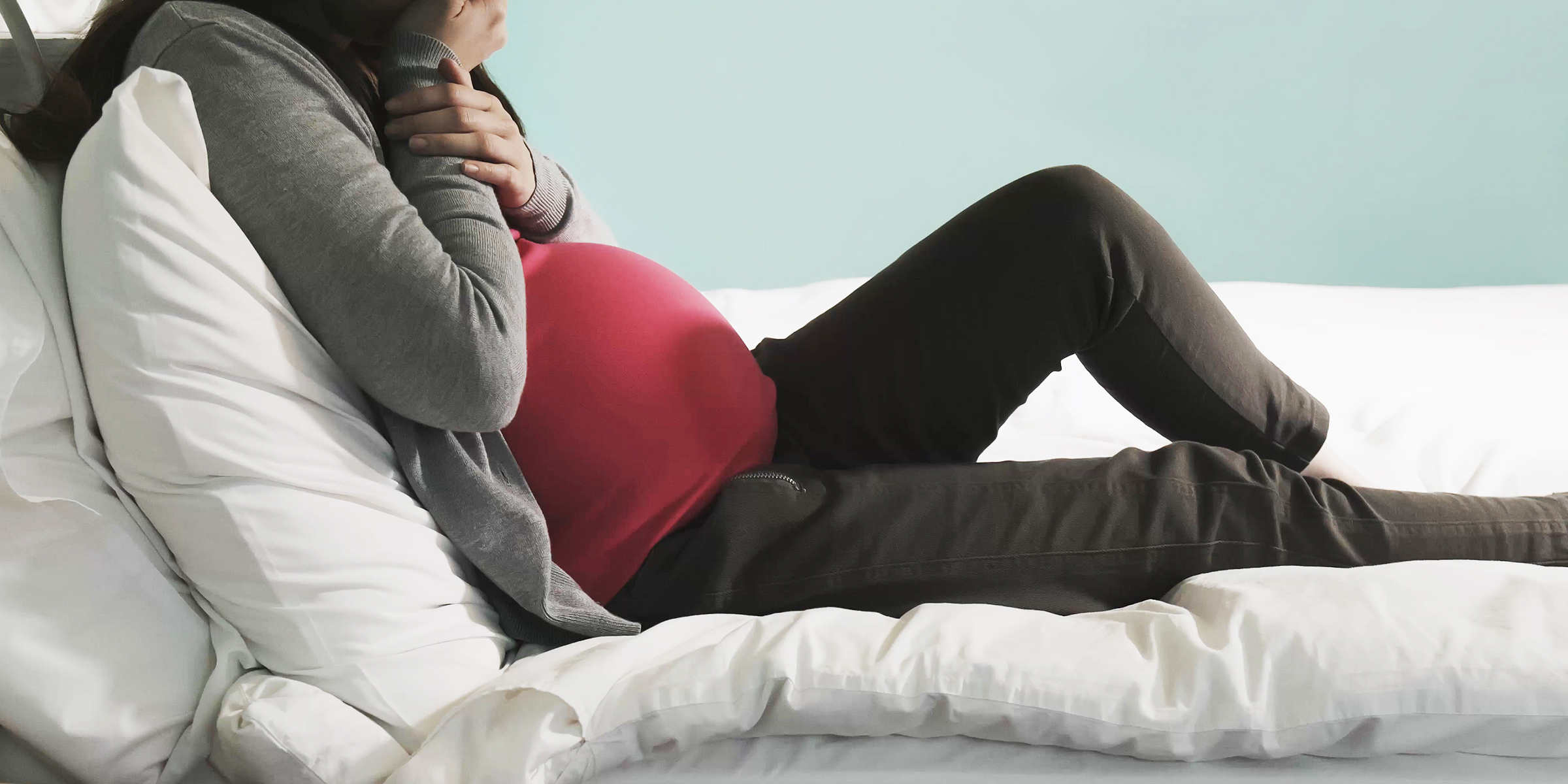 Pregnant woman sitting on a bed | Source: Shutterstock