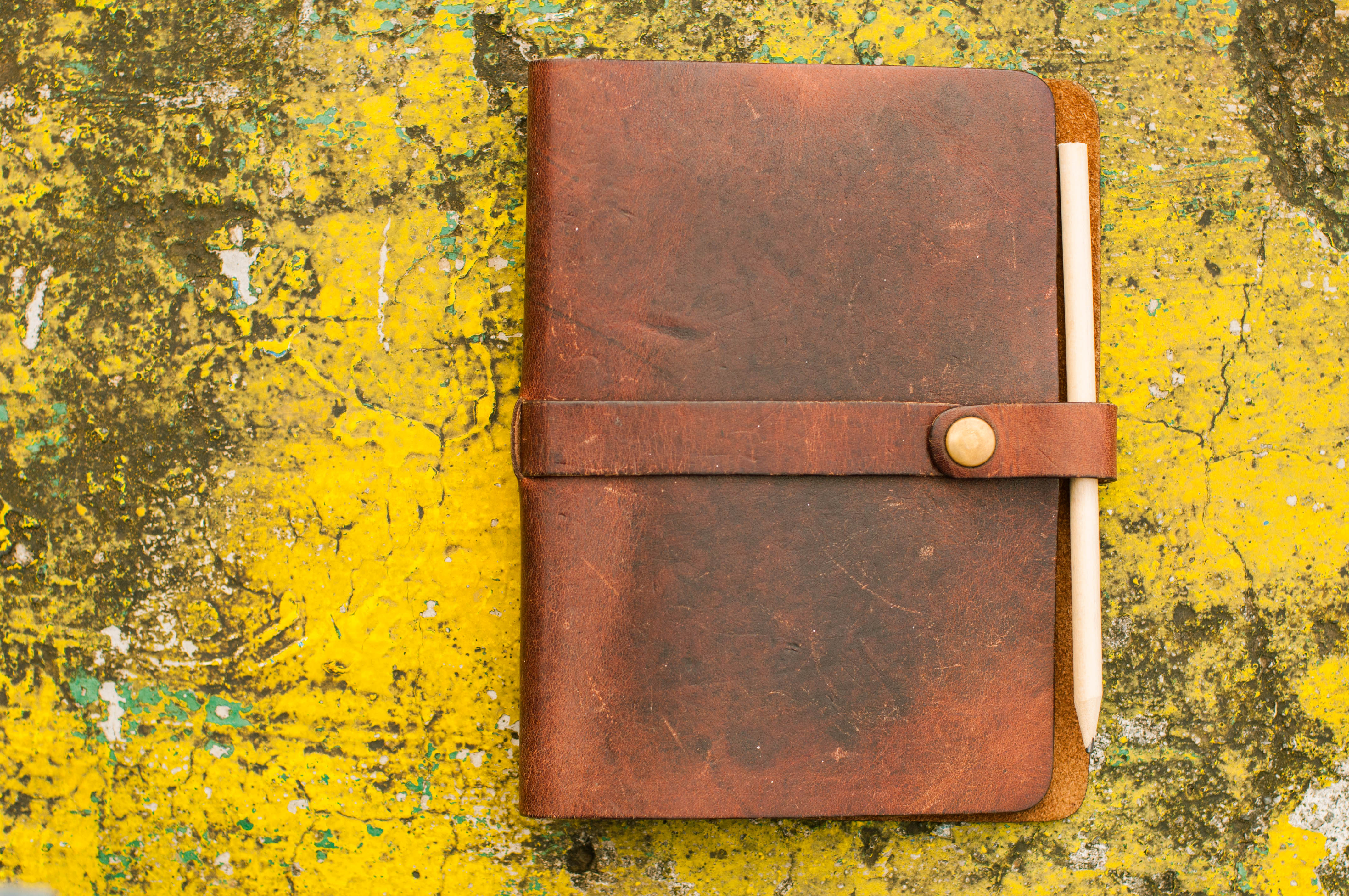Leather-bound personal organizer notepad on a weathered vibrant yellow paint background | Source: Getty Images