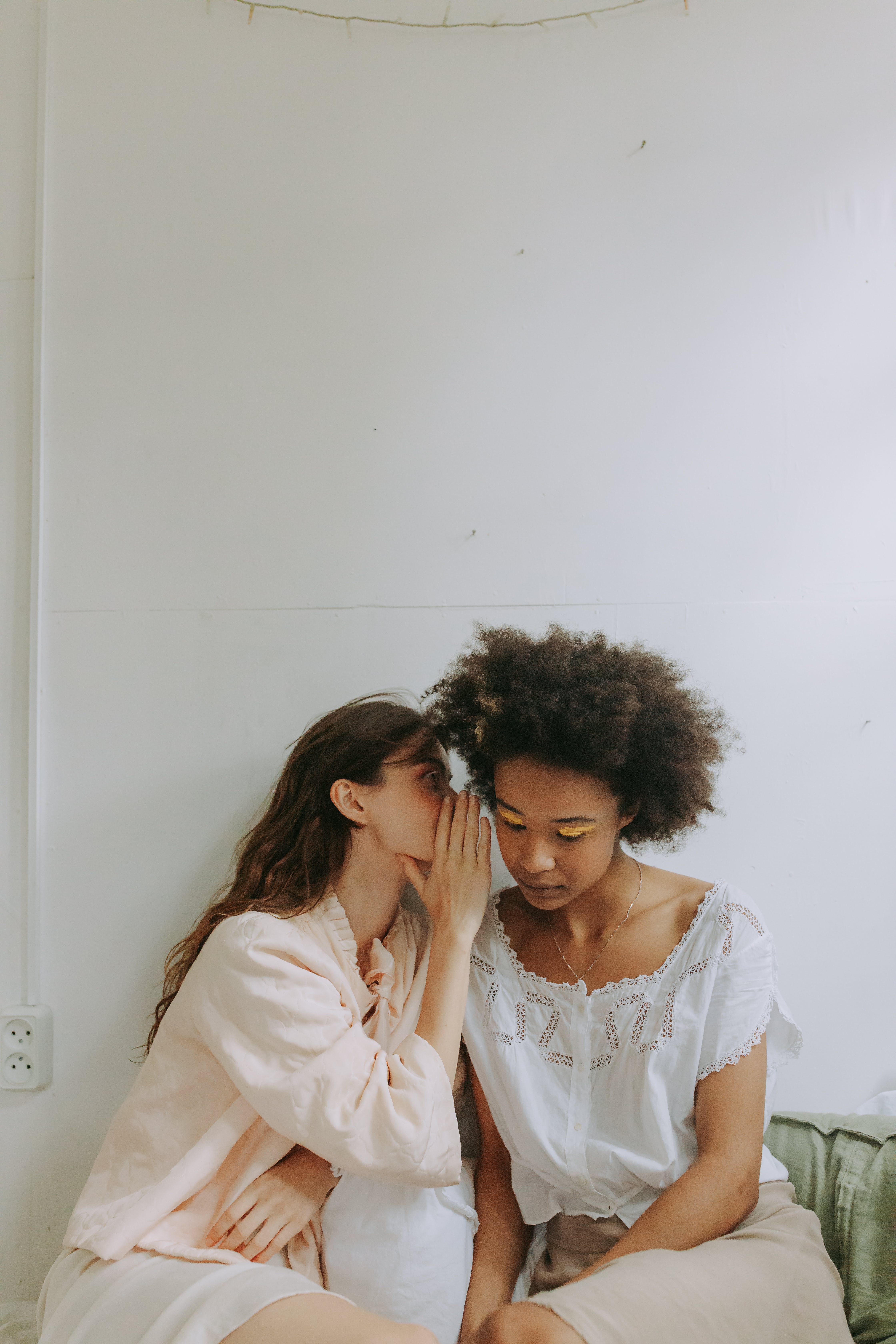 A person whispering to another person's ear. | Source: Pexels