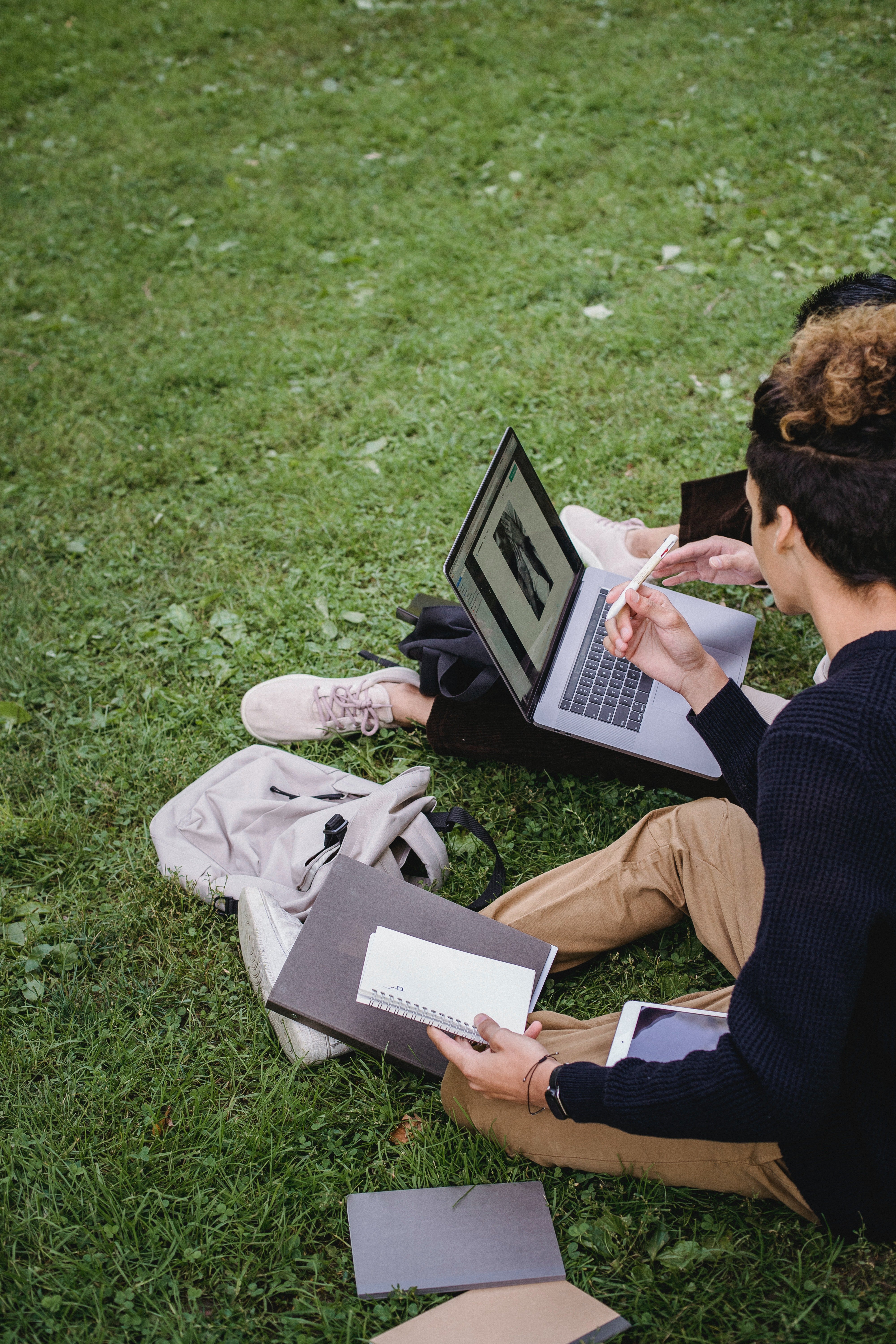 Jóvenes sentados sobre el pasto estudiando. | Foto: Pexels