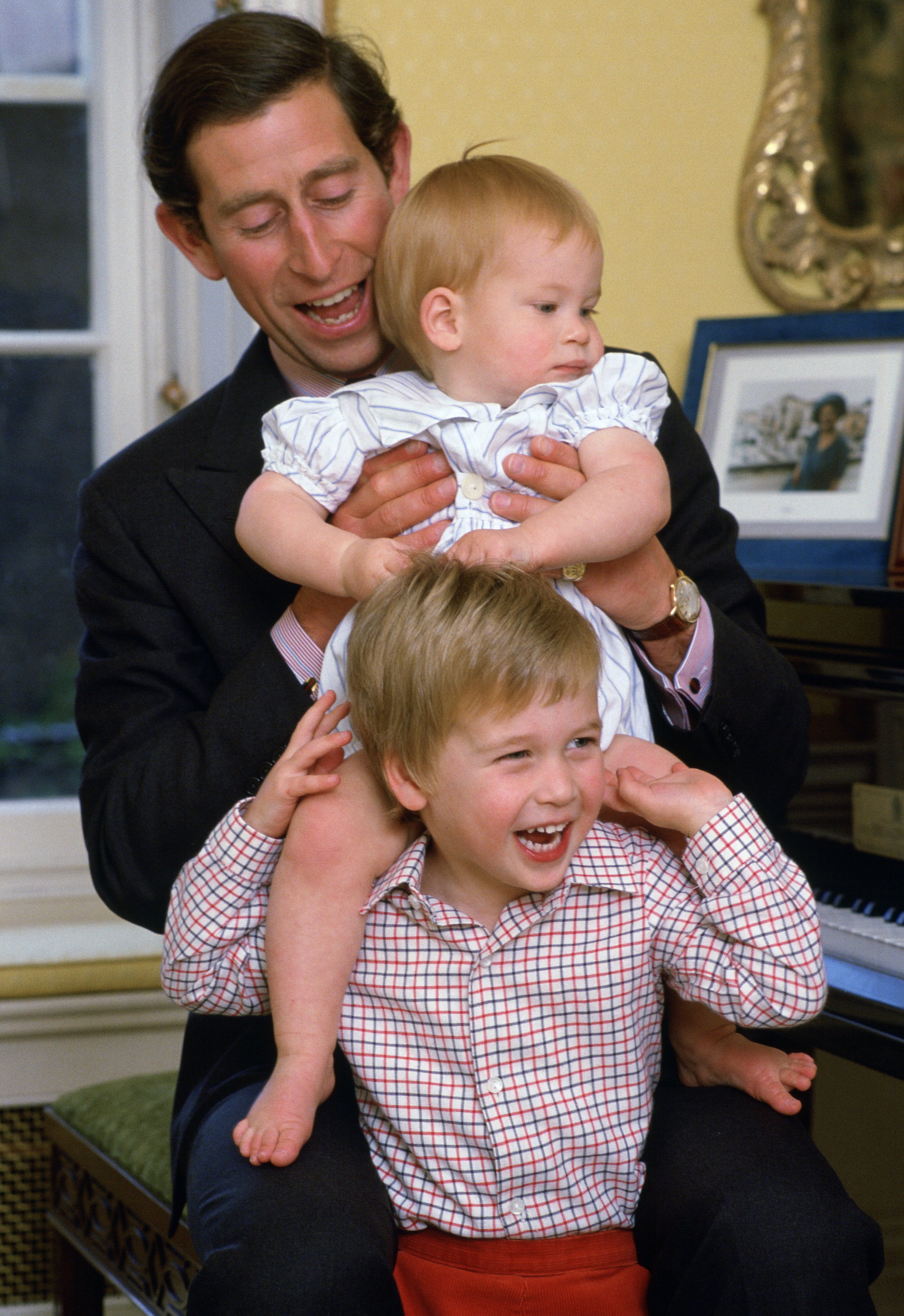  Prinz Charles lacht mit seinen Söhnen, als er Prinz Harry im Kensington Palast auf die Schultern von Prinz William hebt. | Quelle: Getty Images