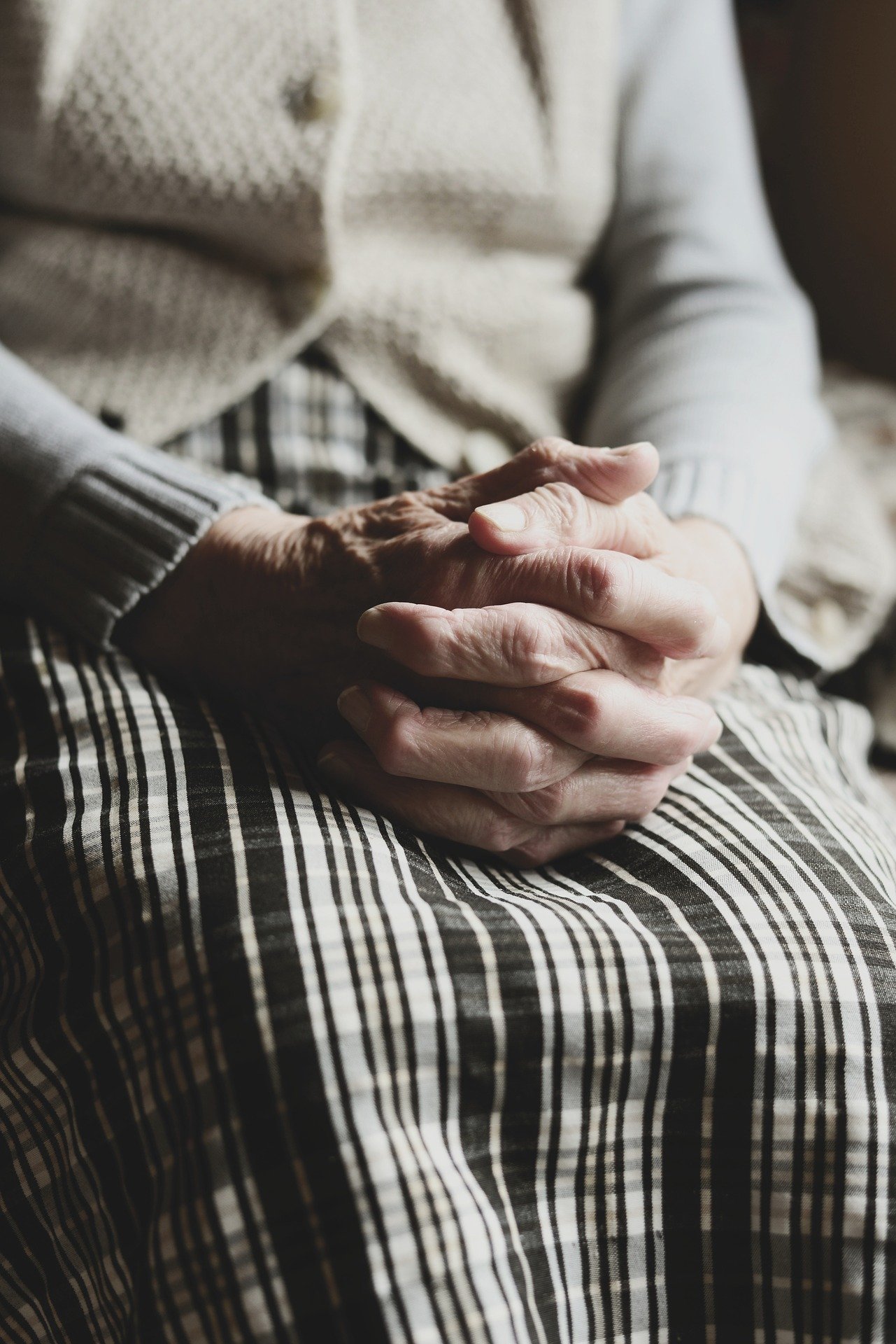 An old woman sitting with her hands clasped together | Photo: Pixabay/congerdesign