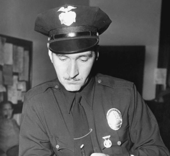 An undated image of Officer Howard Rose looking at purse belonging to missing model and actress, Jean Spangler | Photo: Getty Images