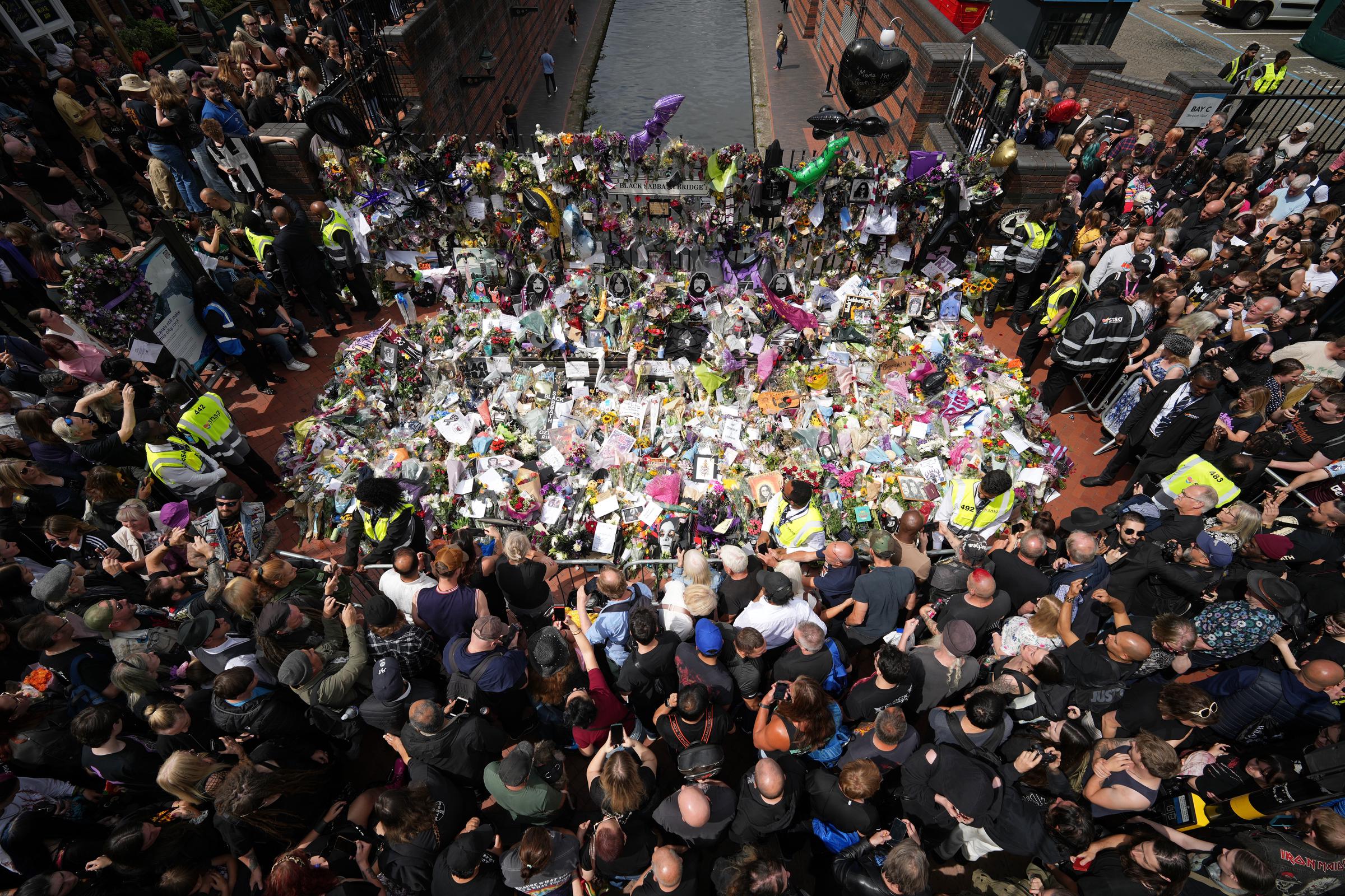 Fans view tributes to the late Ozzy Osbourne at the Black Sabbath Bench and Bridge as his funeral cortege travels through Birmingham on July 30, 2025, in Birmingham, England | Source: Getty Images