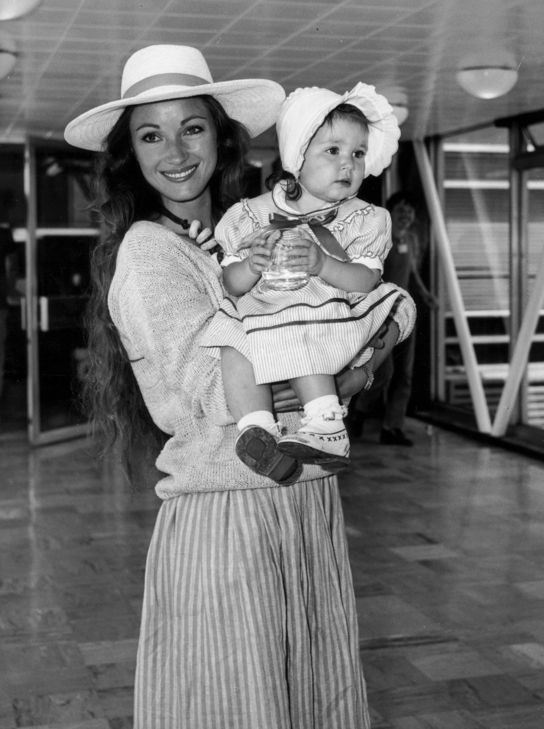 The actress poses with her daughter, Katie, at Heathrow Airport before heading to California in July 1983. | Source: Getty Images