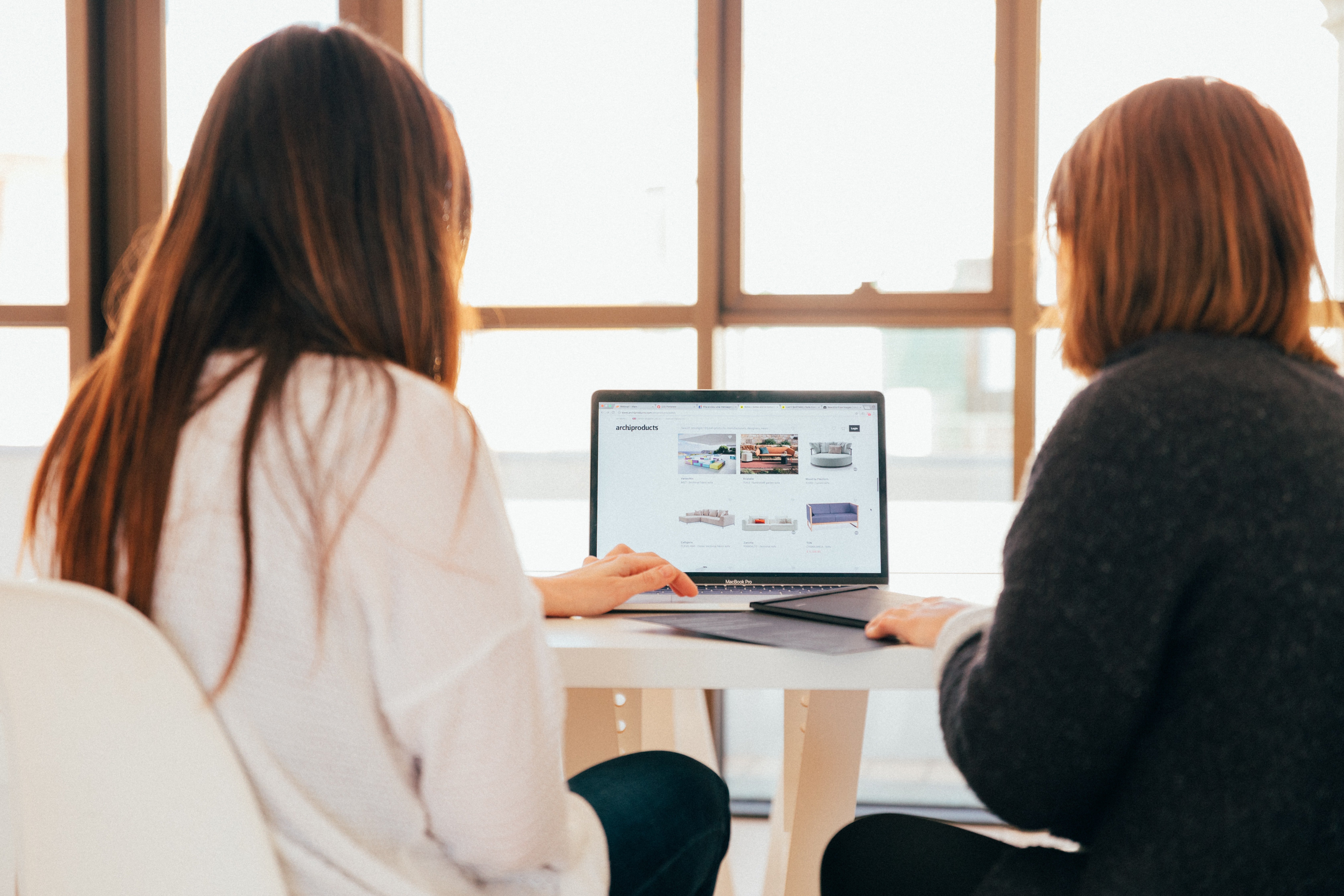 Two women talking and looking at the computer | Source: Unsplash / KOBU Agency 