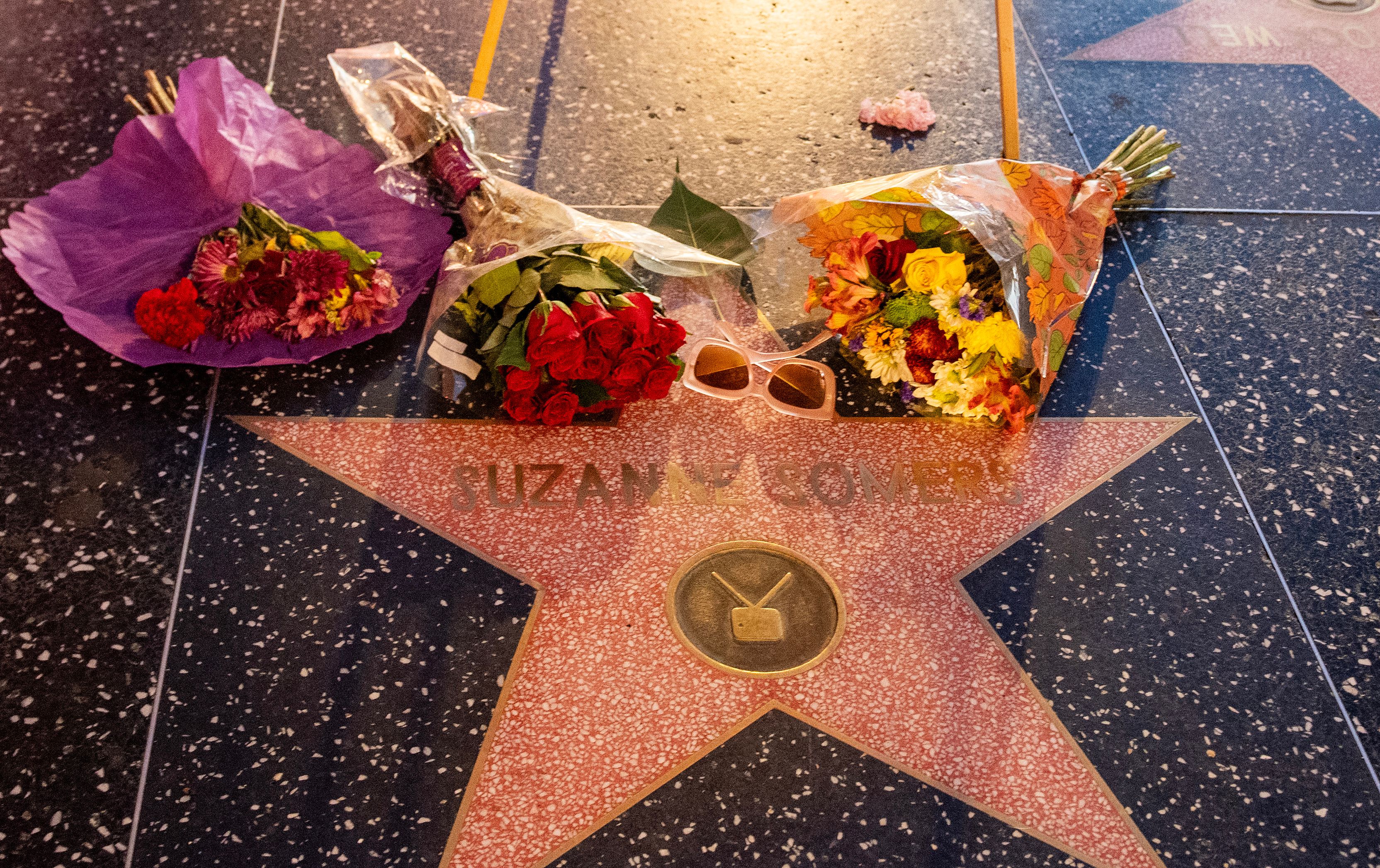 Bouquets of flowers and a pair of sunglasses laid on Suzanne Somers' Hollywood Walk of Fame star placed in memory of her in Hollywood, California on October 16, 2023 | Source: Getty Images