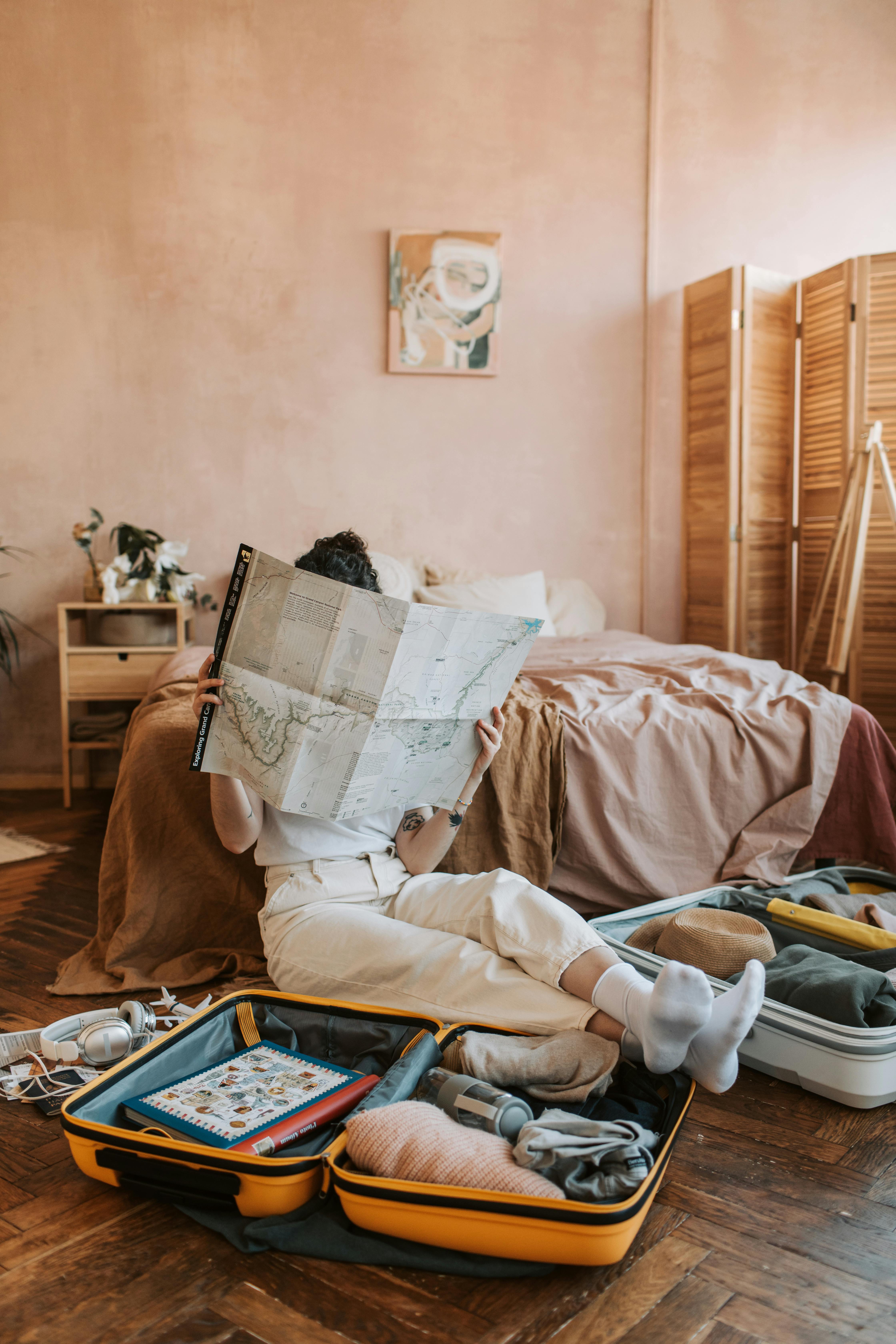 A woman looking at a map while packing her luggage | Source: Pexels